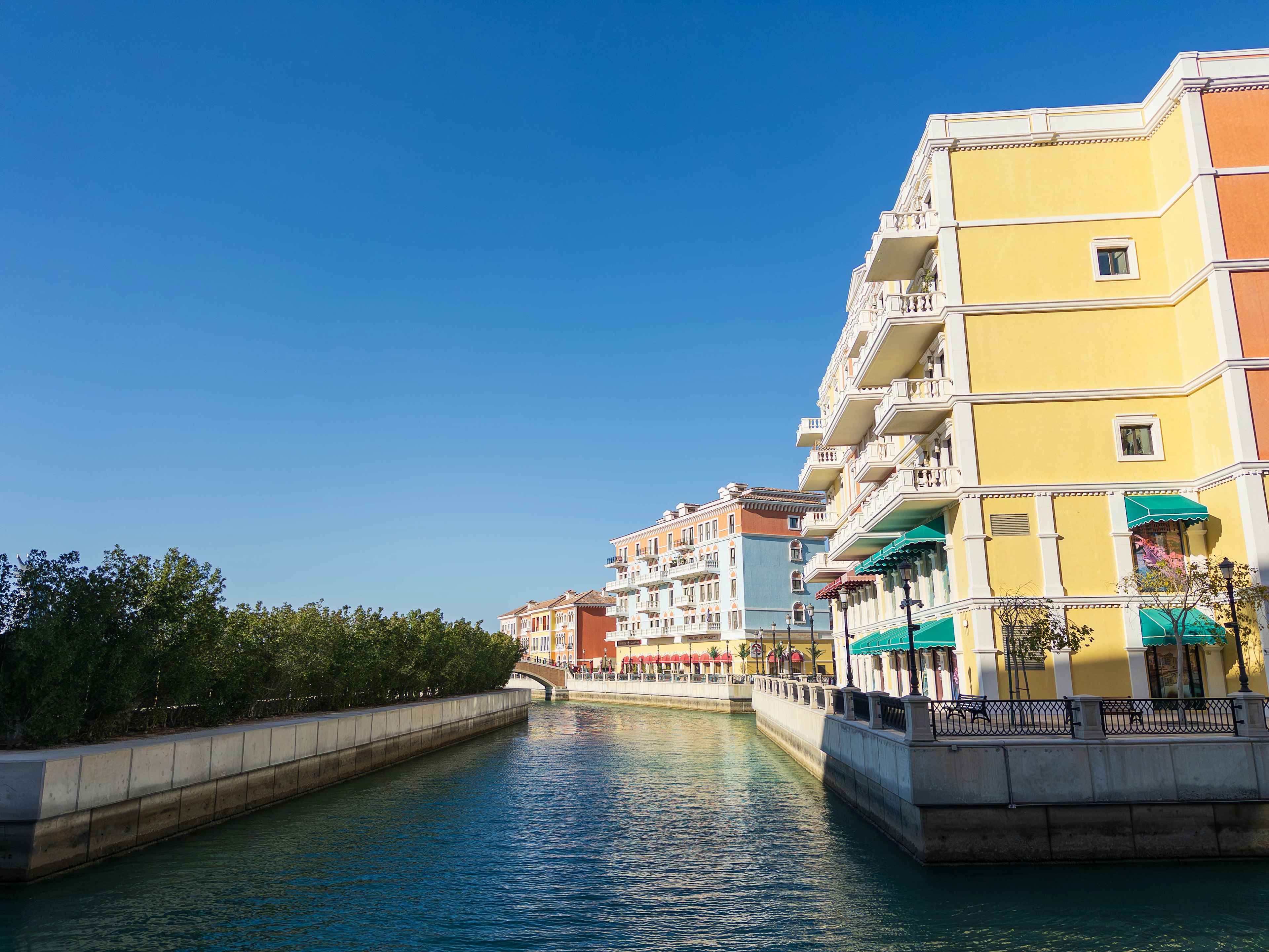 Colorful buildings along a canal under a clear blue sky