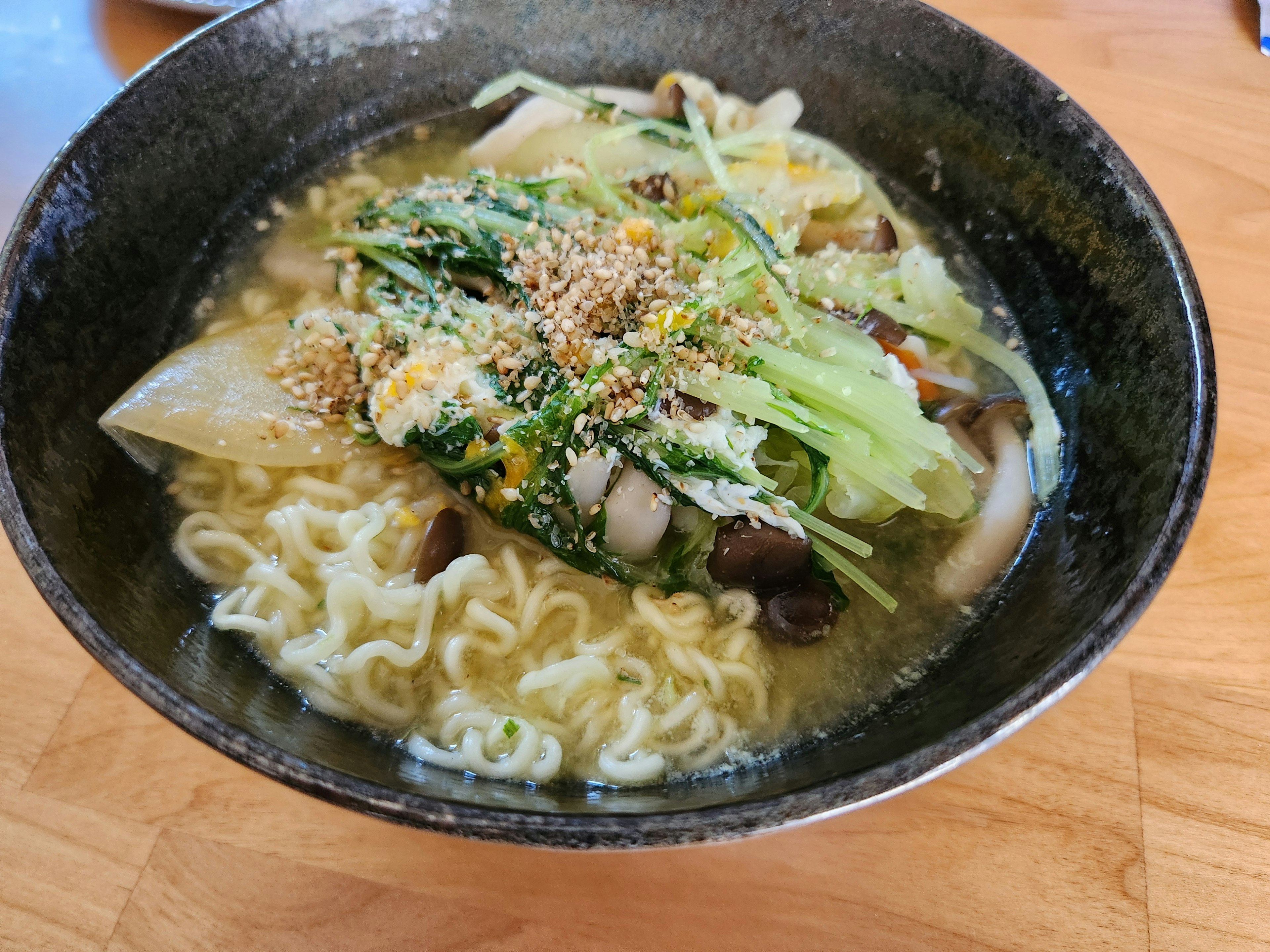 Bowl of ramen with fresh vegetables and garnished broth