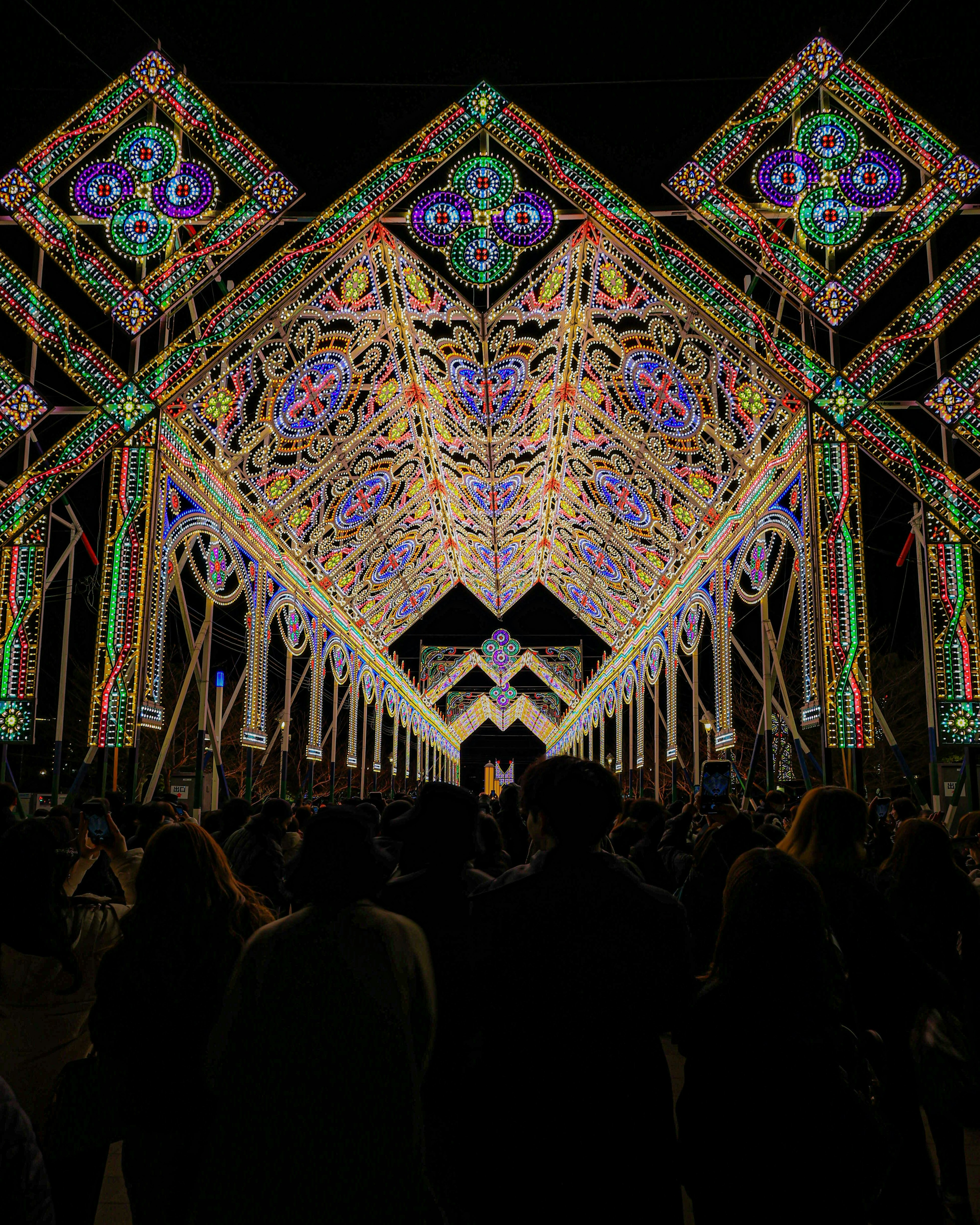 夜の祭りのために飾られた美しい光のアーチと観客