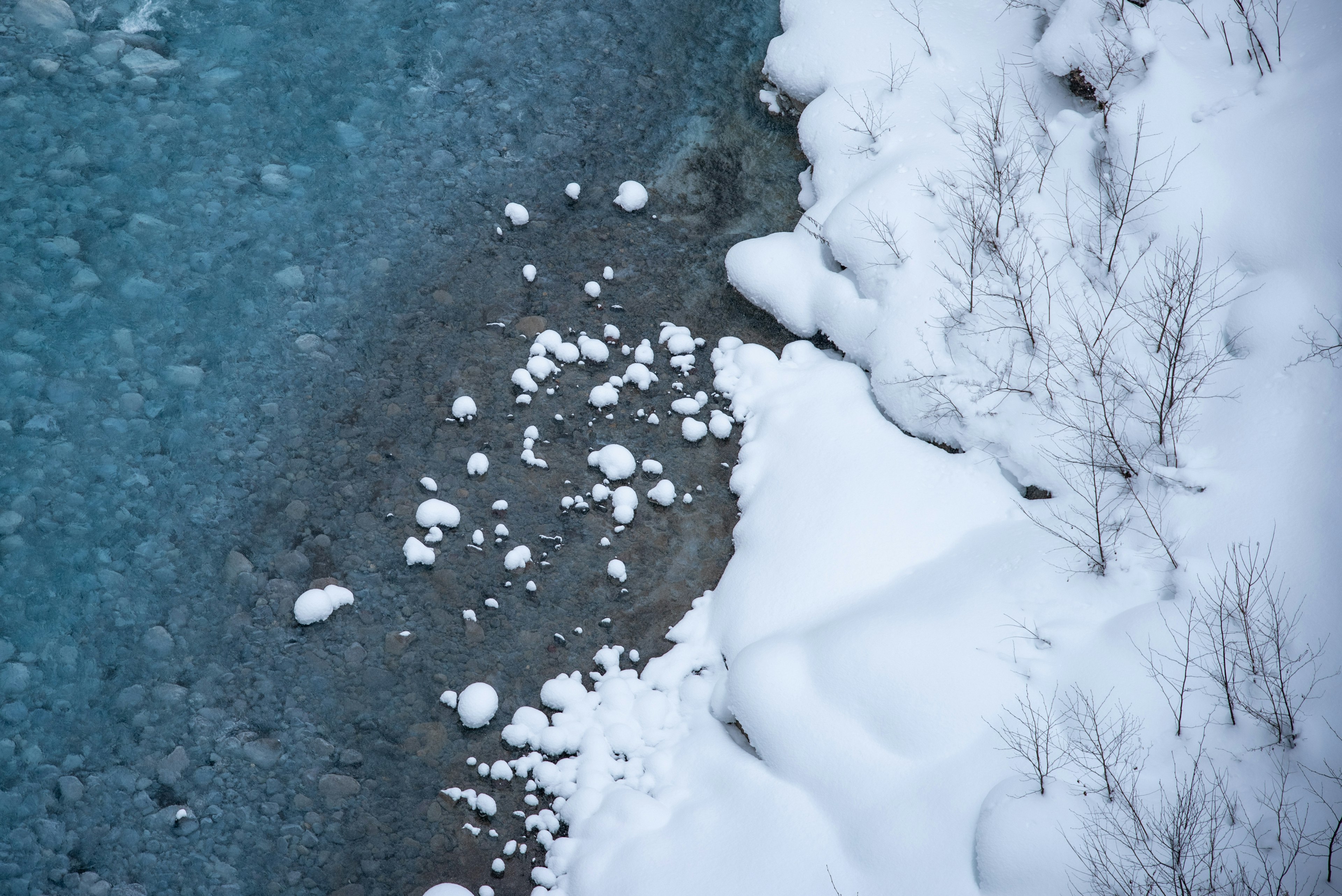 Winter landscape with snowy riverbank and flowing blue water