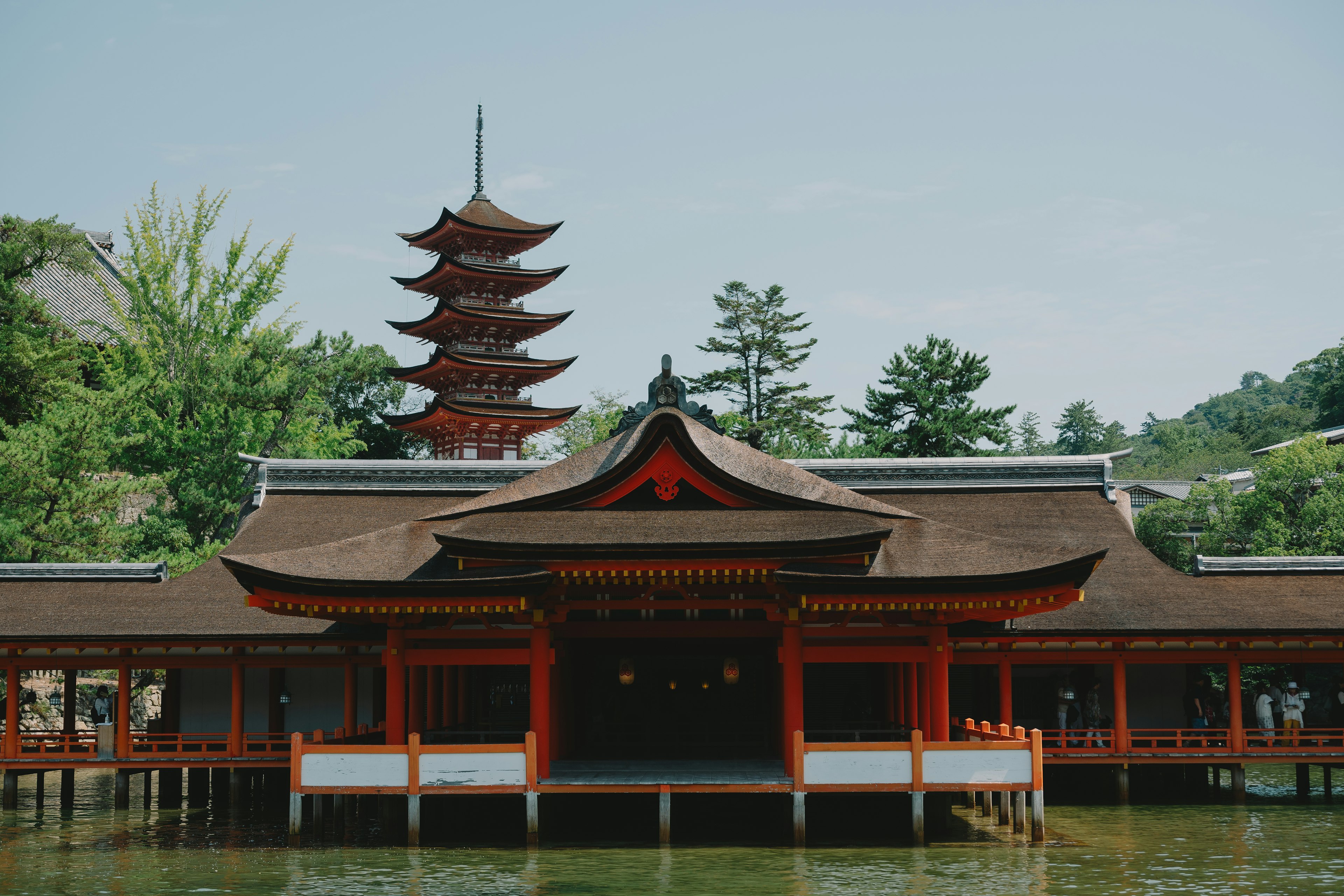 Traditional Japanese building on water with a pagoda in the background