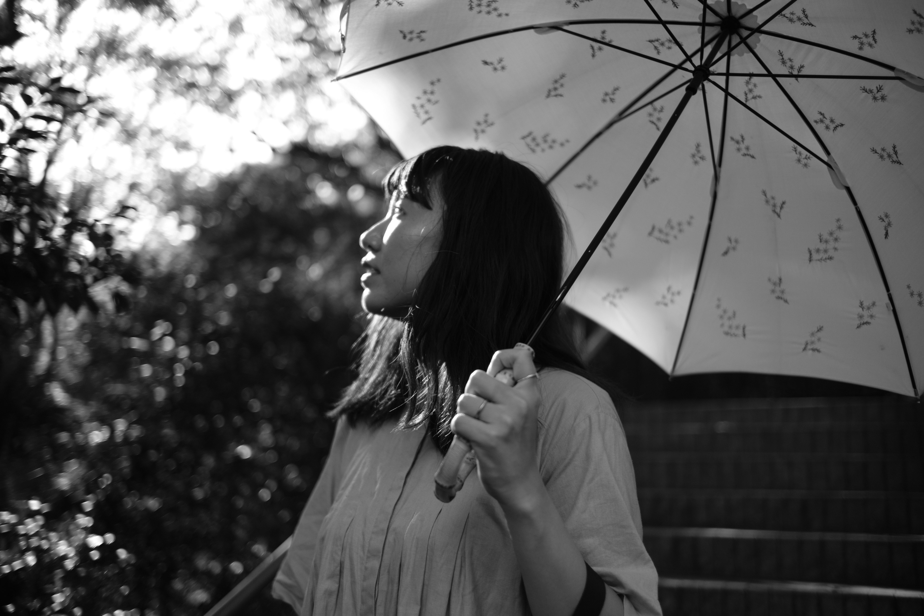 Ein schwarz-weiß Foto einer Frau mit einem Regenschirm, die zum Himmel schaut