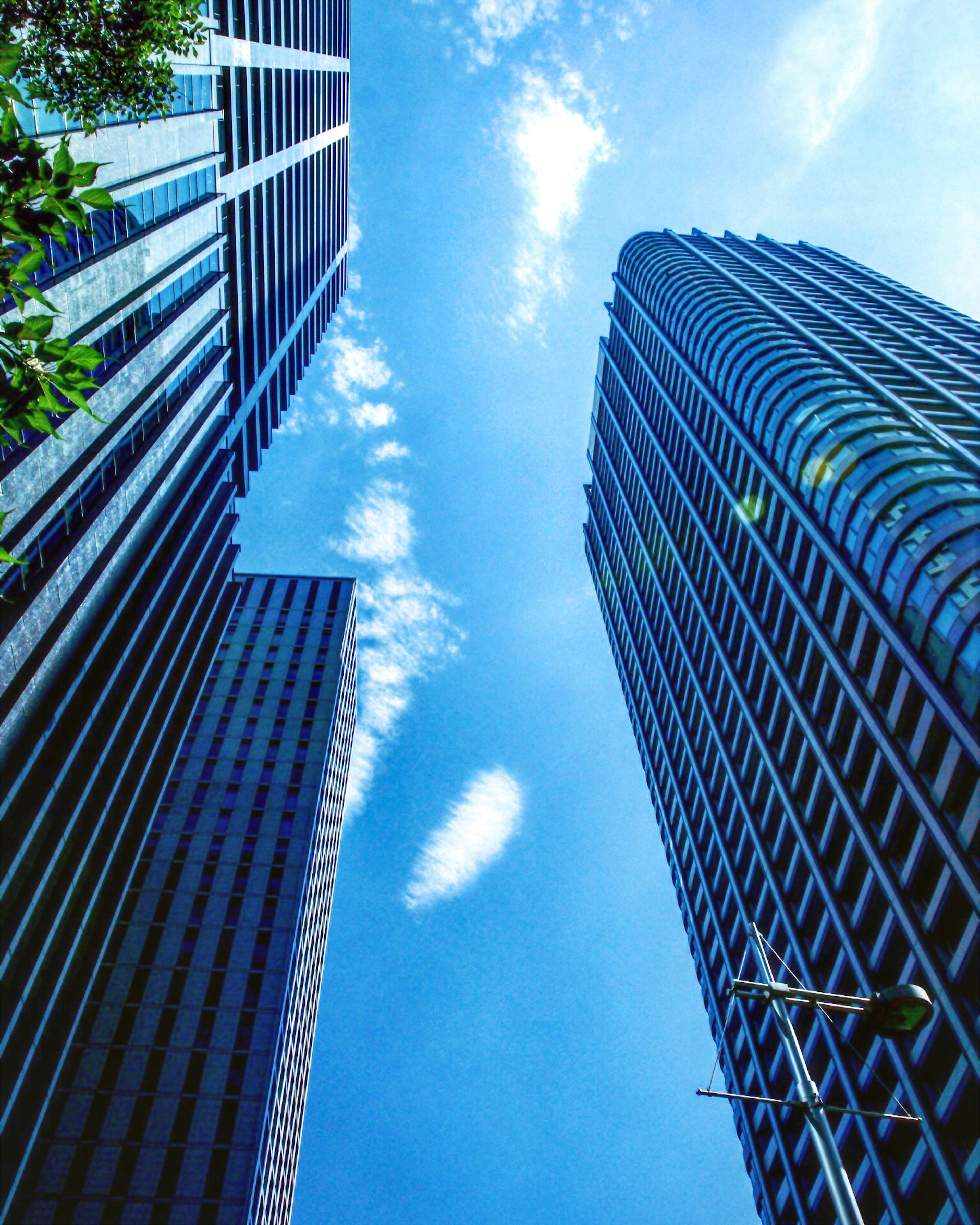 View looking up at skyscrapers against a blue sky