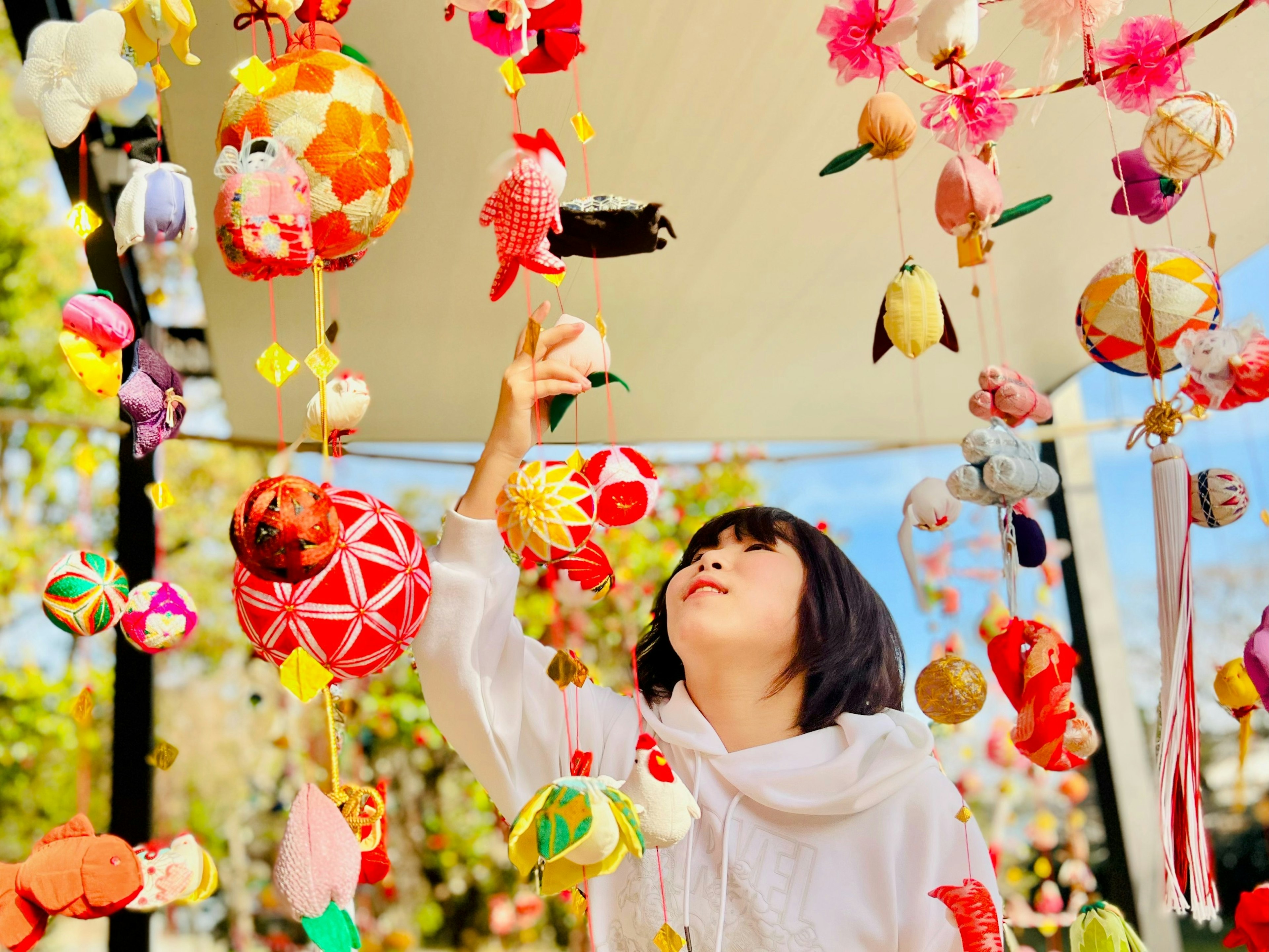 Una niña alcanzando decoraciones coloridas colgantes