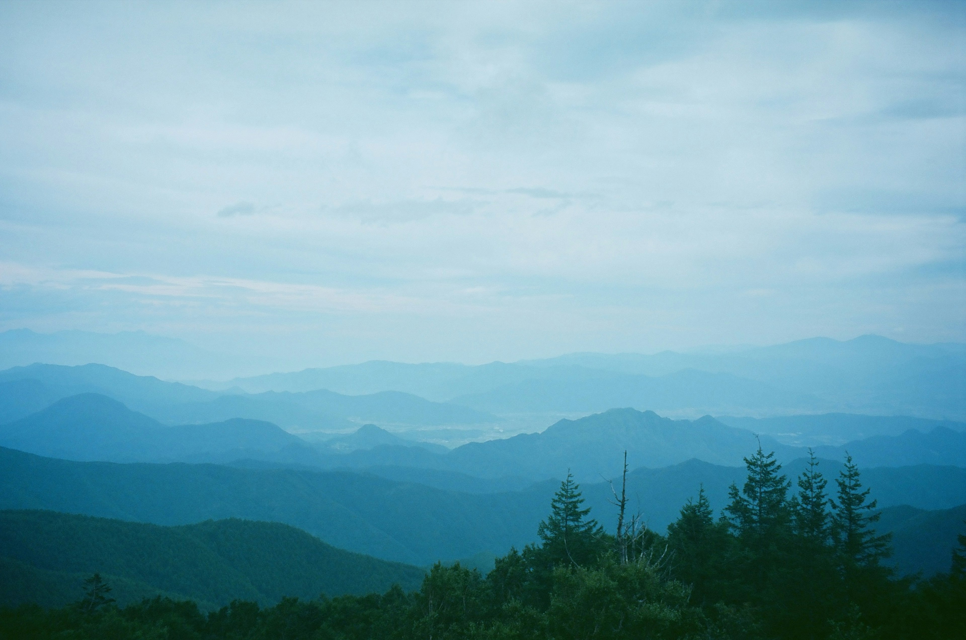 Foggy landscape with blue mountains and cloudy sky