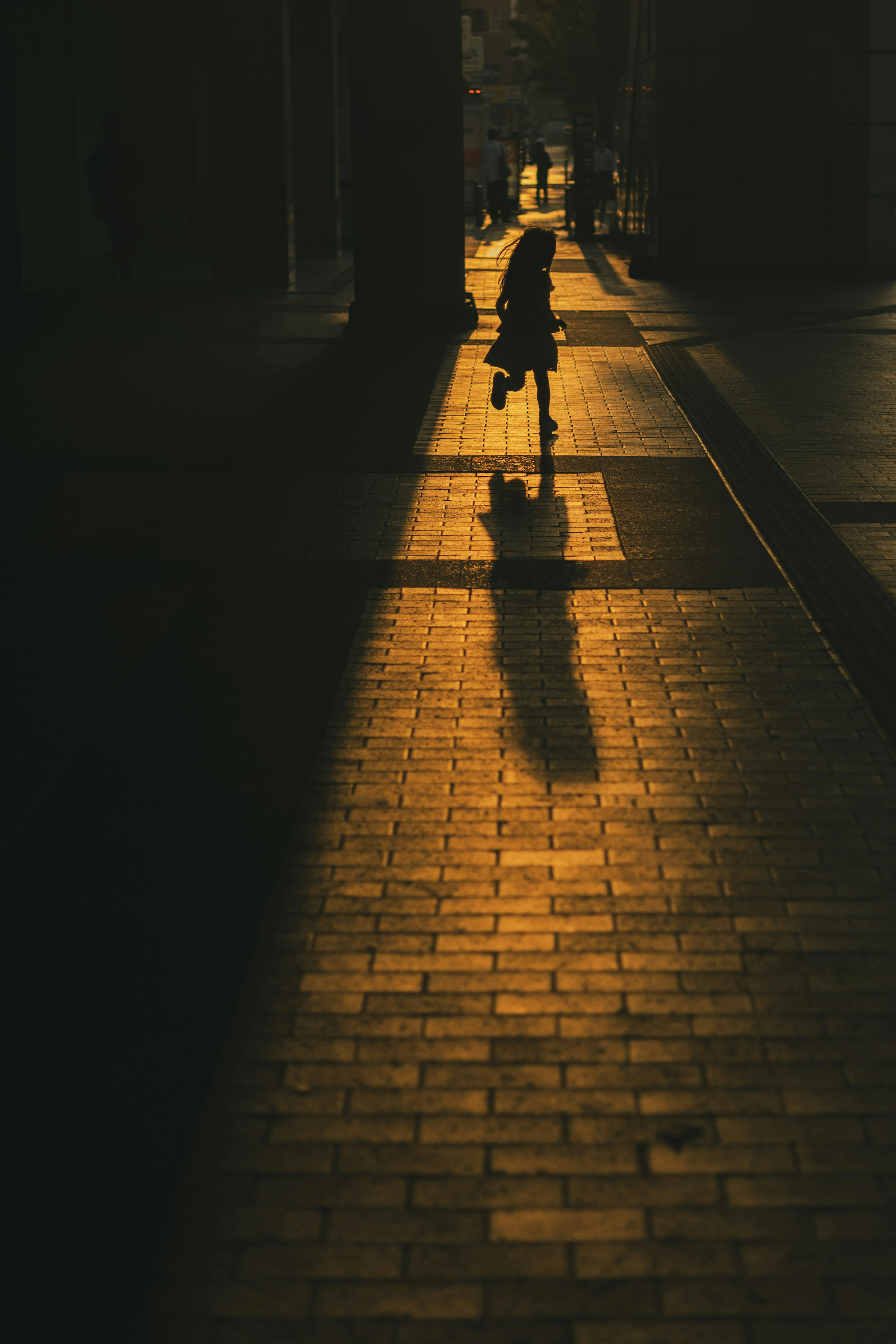 Siluet seorang berjalan di kota saat matahari terbenam dengan bayangan