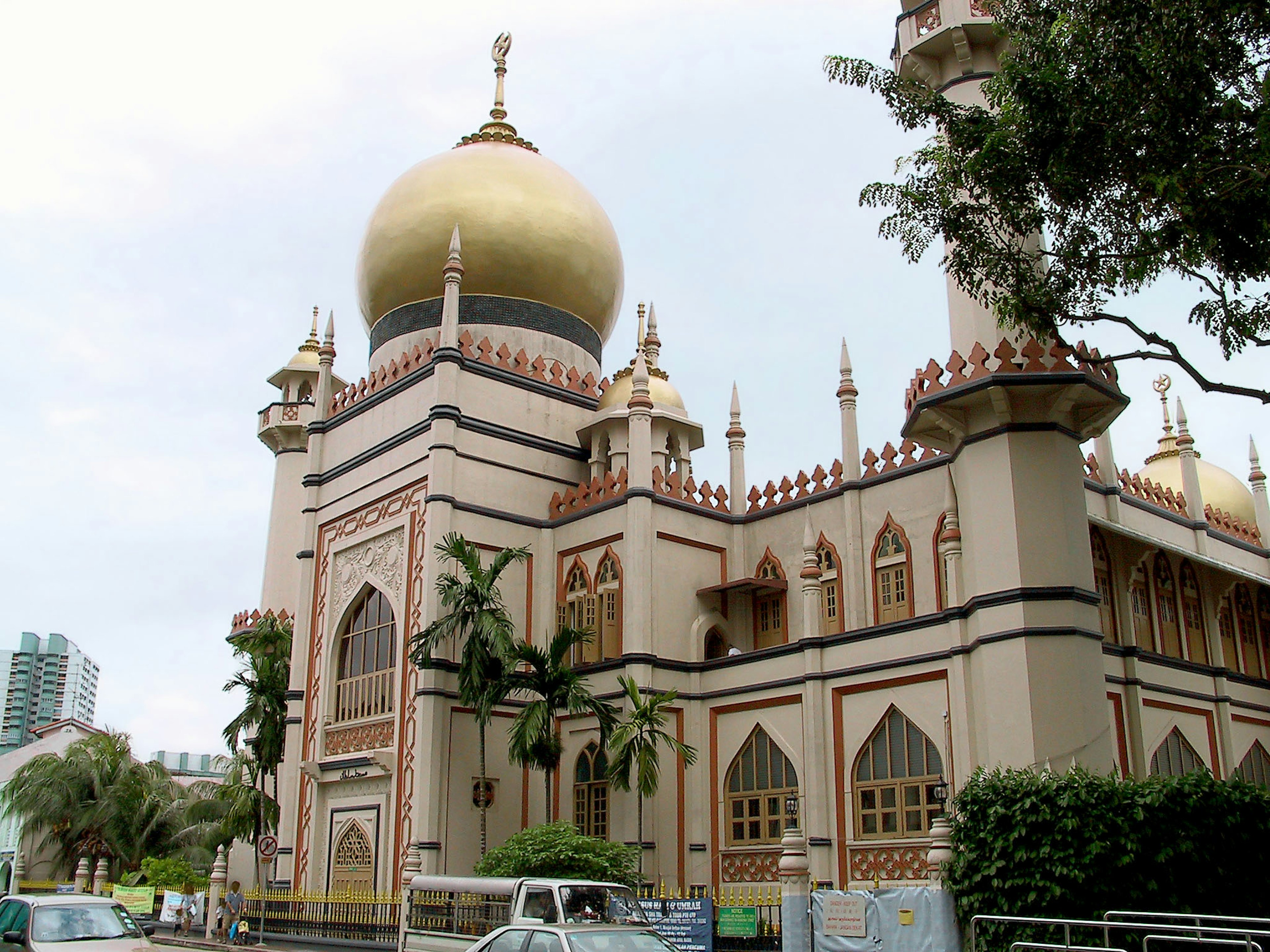 Extérieur d'une belle mosquée avec un dôme doré entouré de plantes vertes