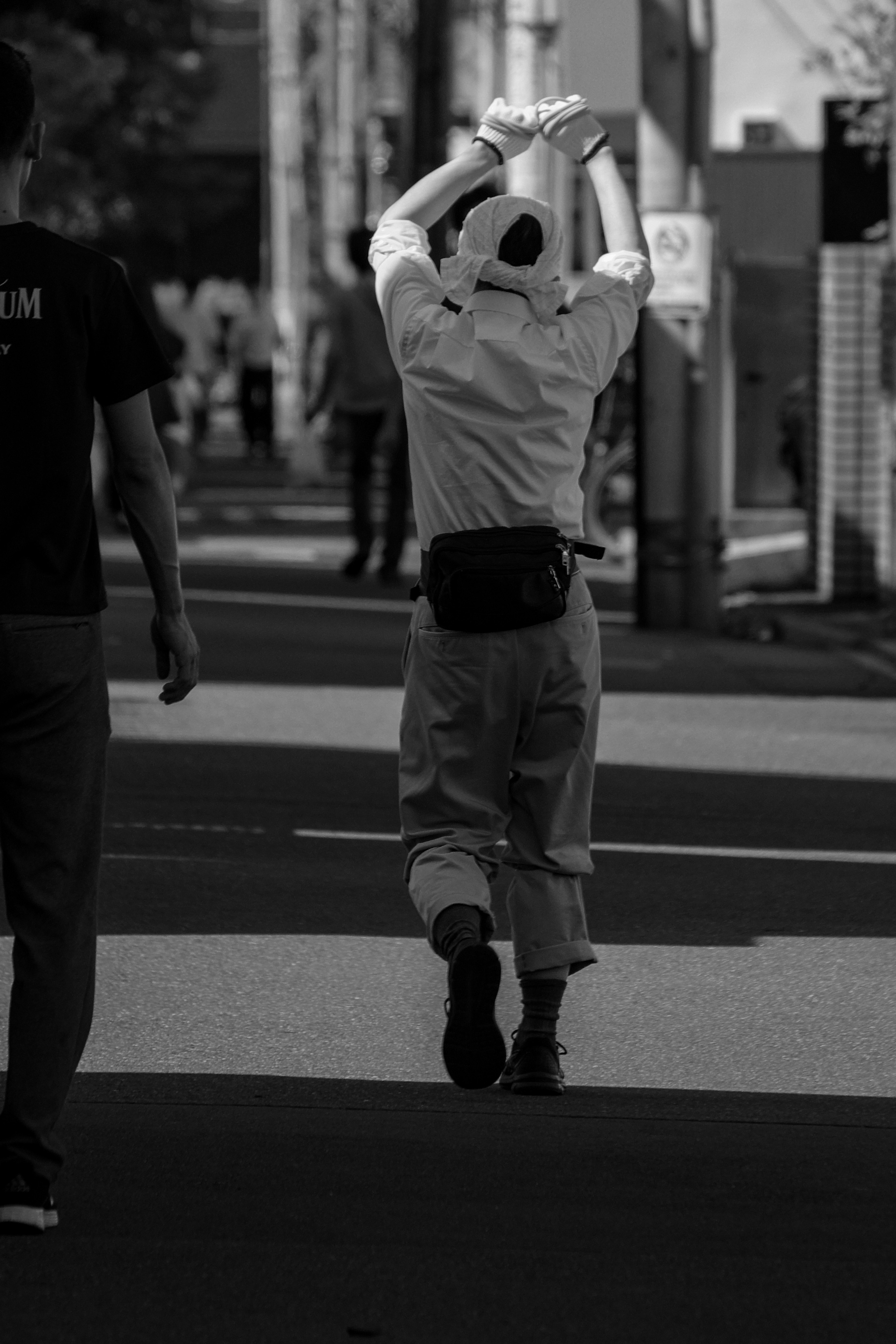 A person in white clothing walking away in a city street