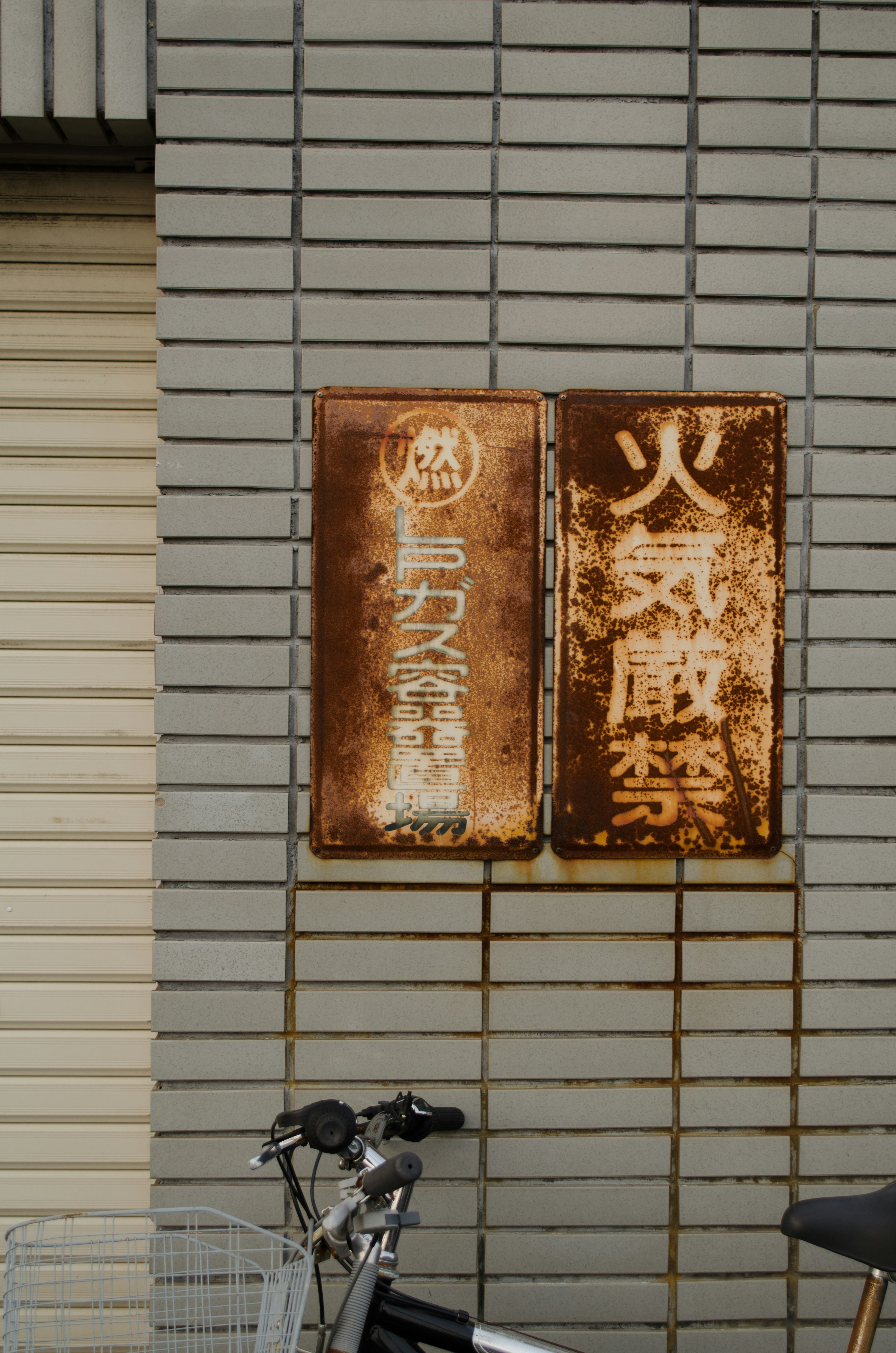 Rusty signs on a brick wall with a bicycle