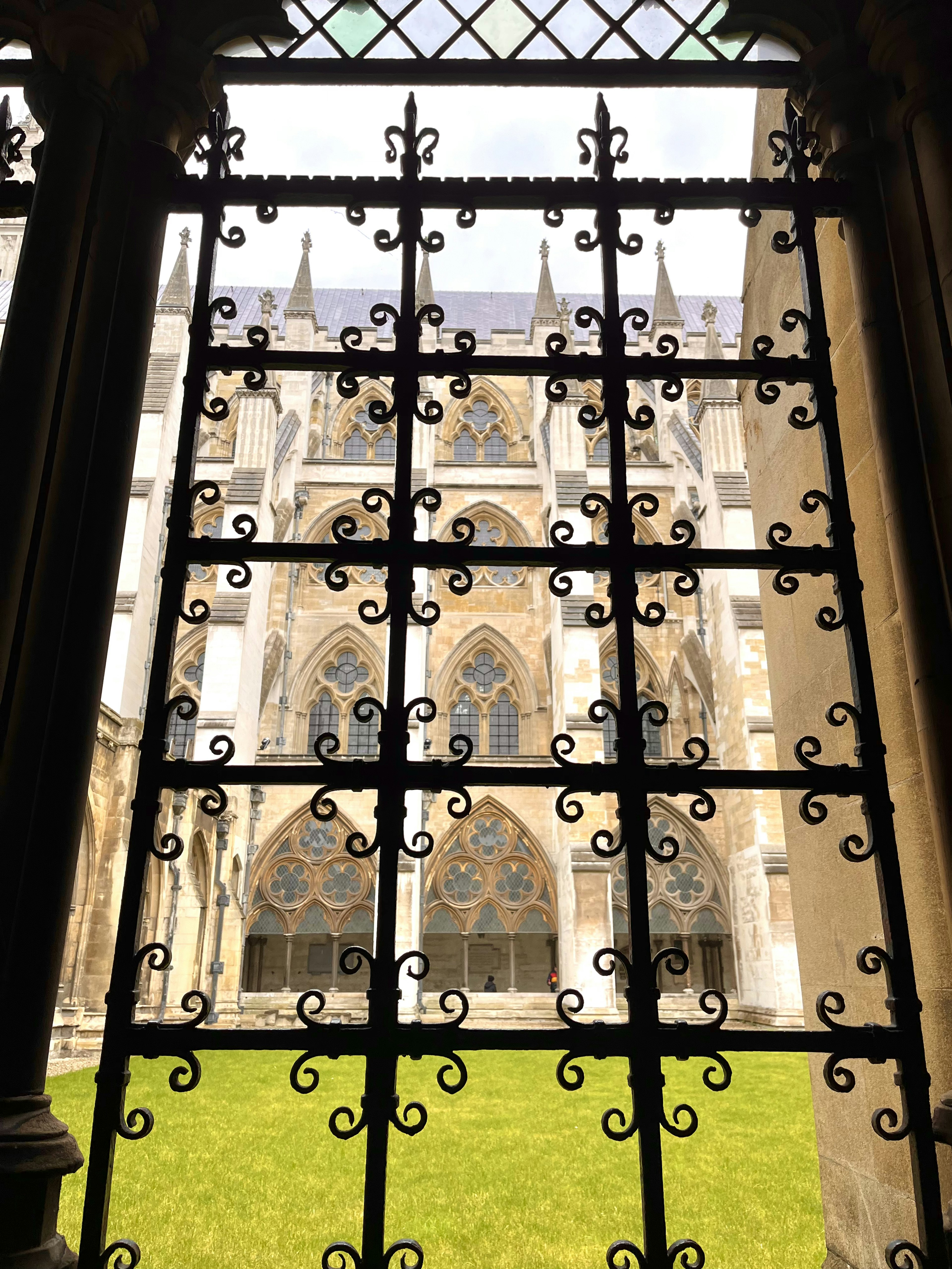 Vista de un patio a través de una ventana de hierro decorativa de una catedral