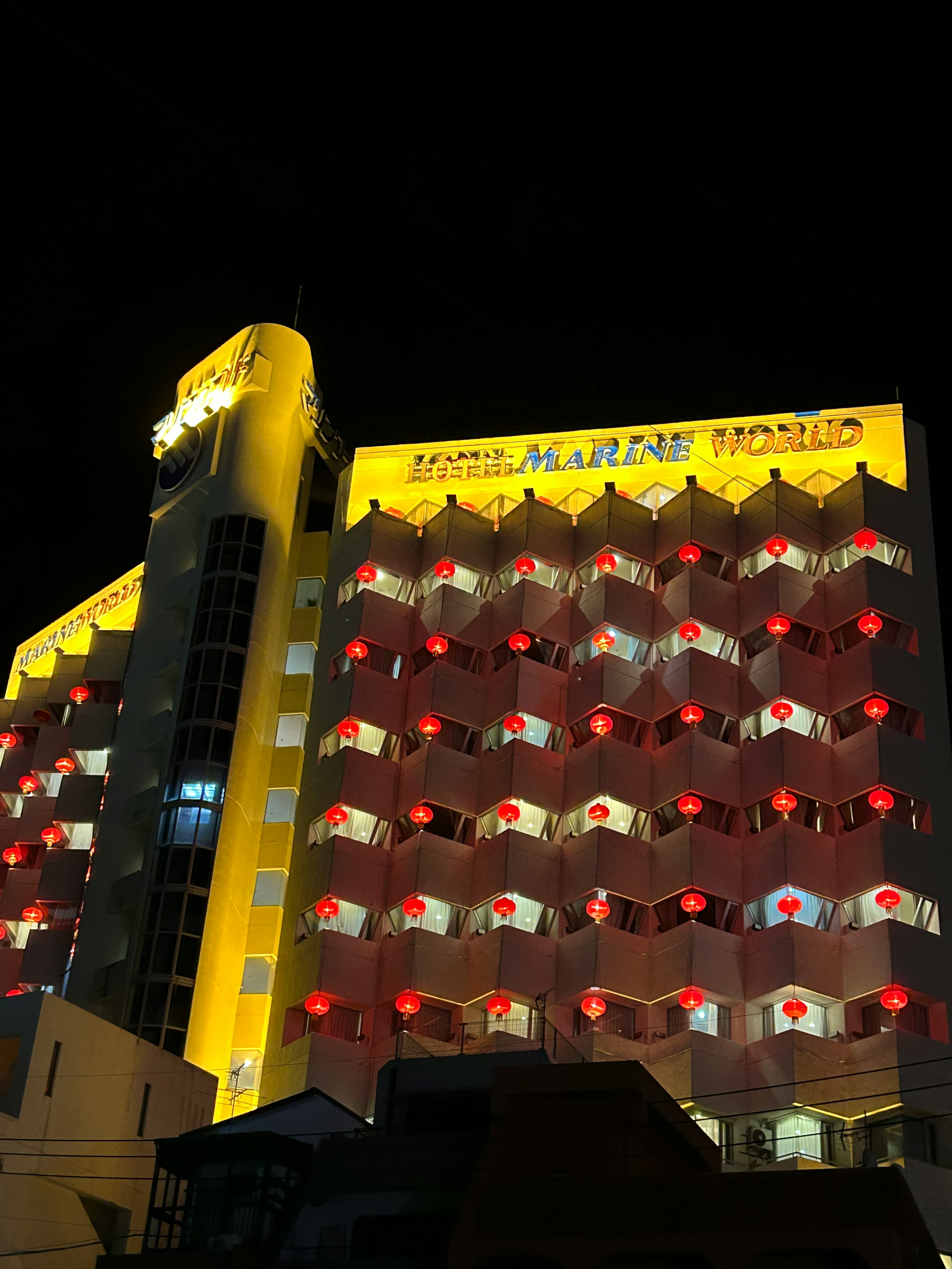 Illuminated hotel facade at night with red and white balcony decorations