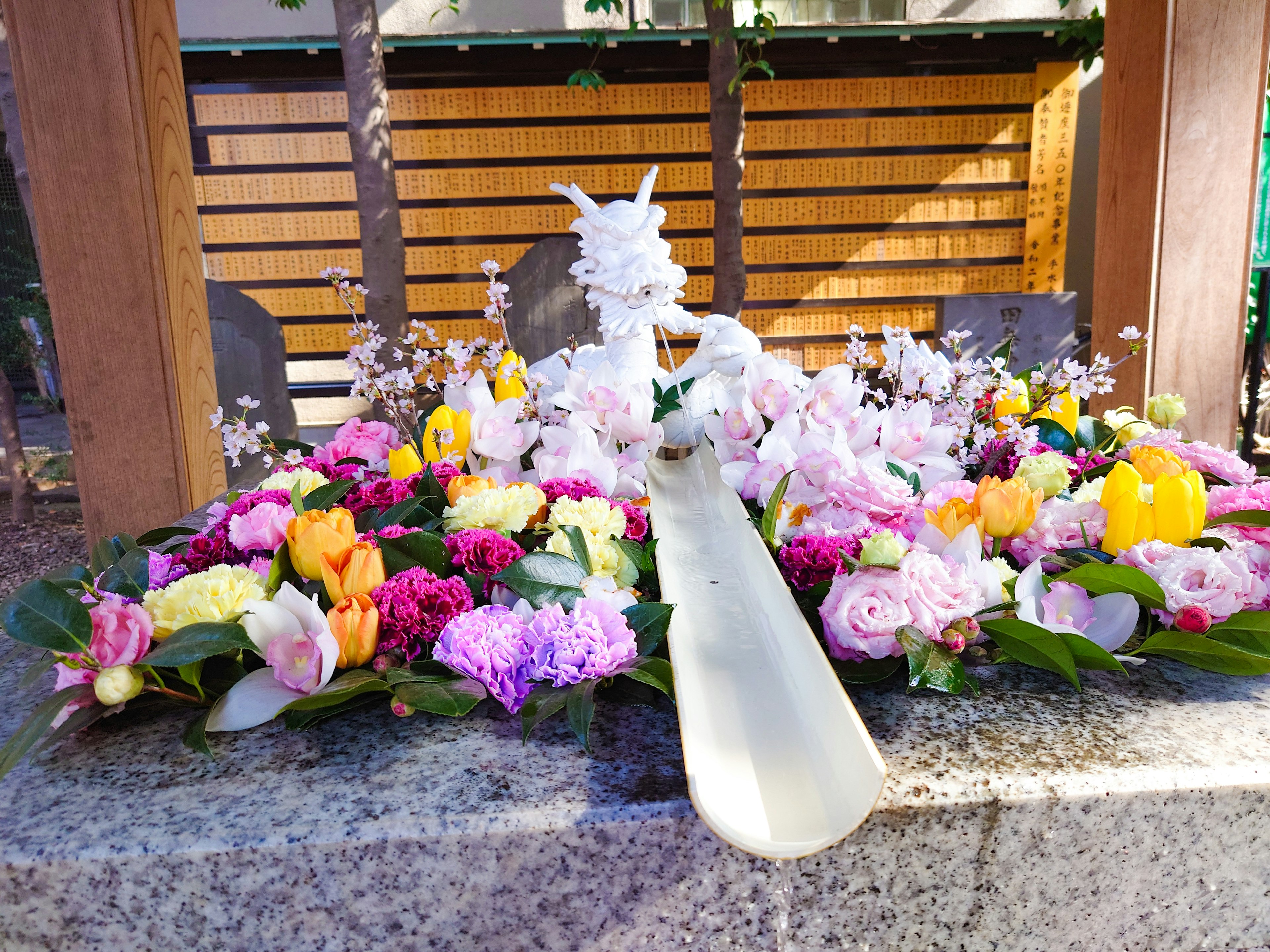 A white dragon sculpture surrounded by colorful flowers