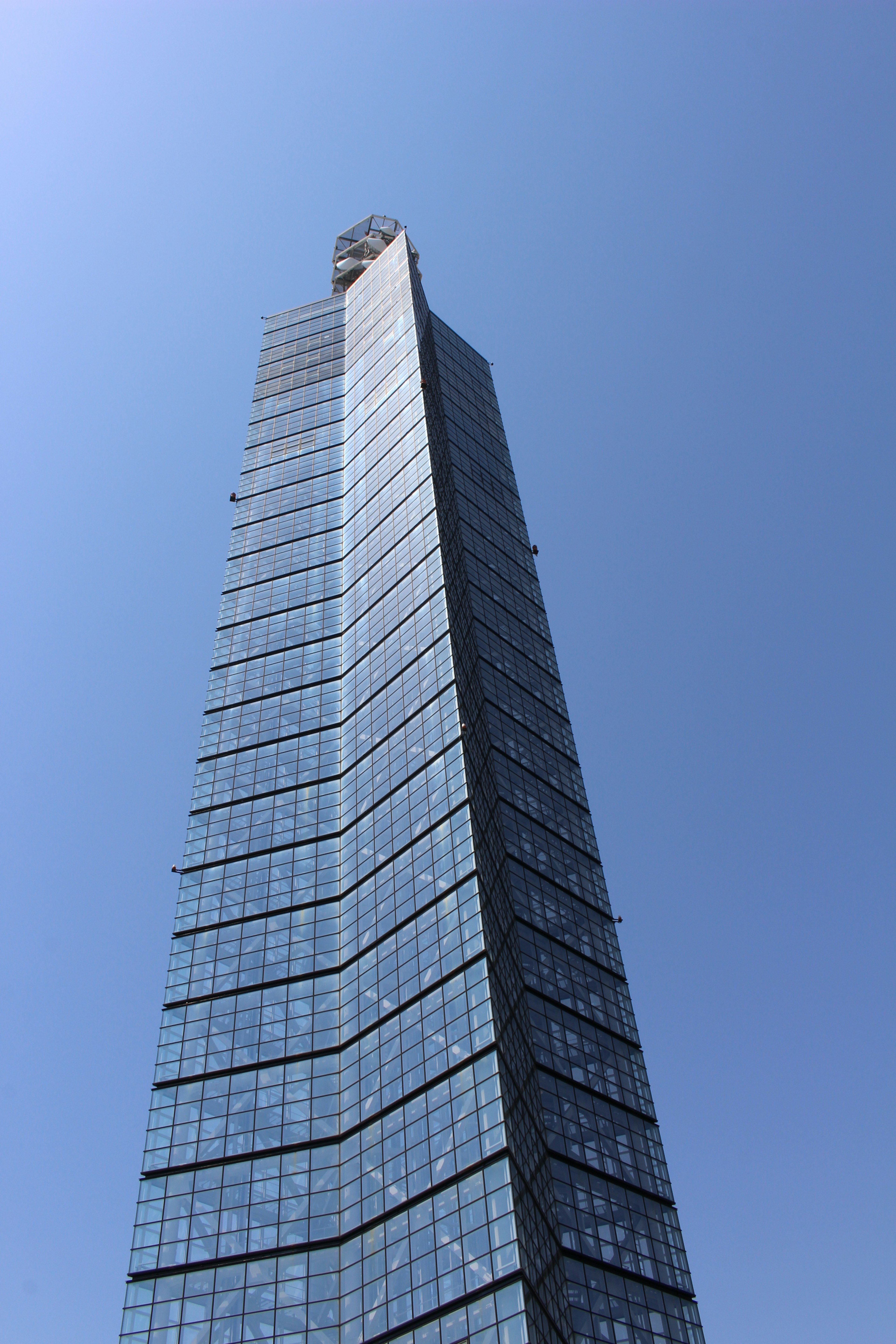 Gedung pencakar langit tinggi dengan fasad kaca dan langit biru