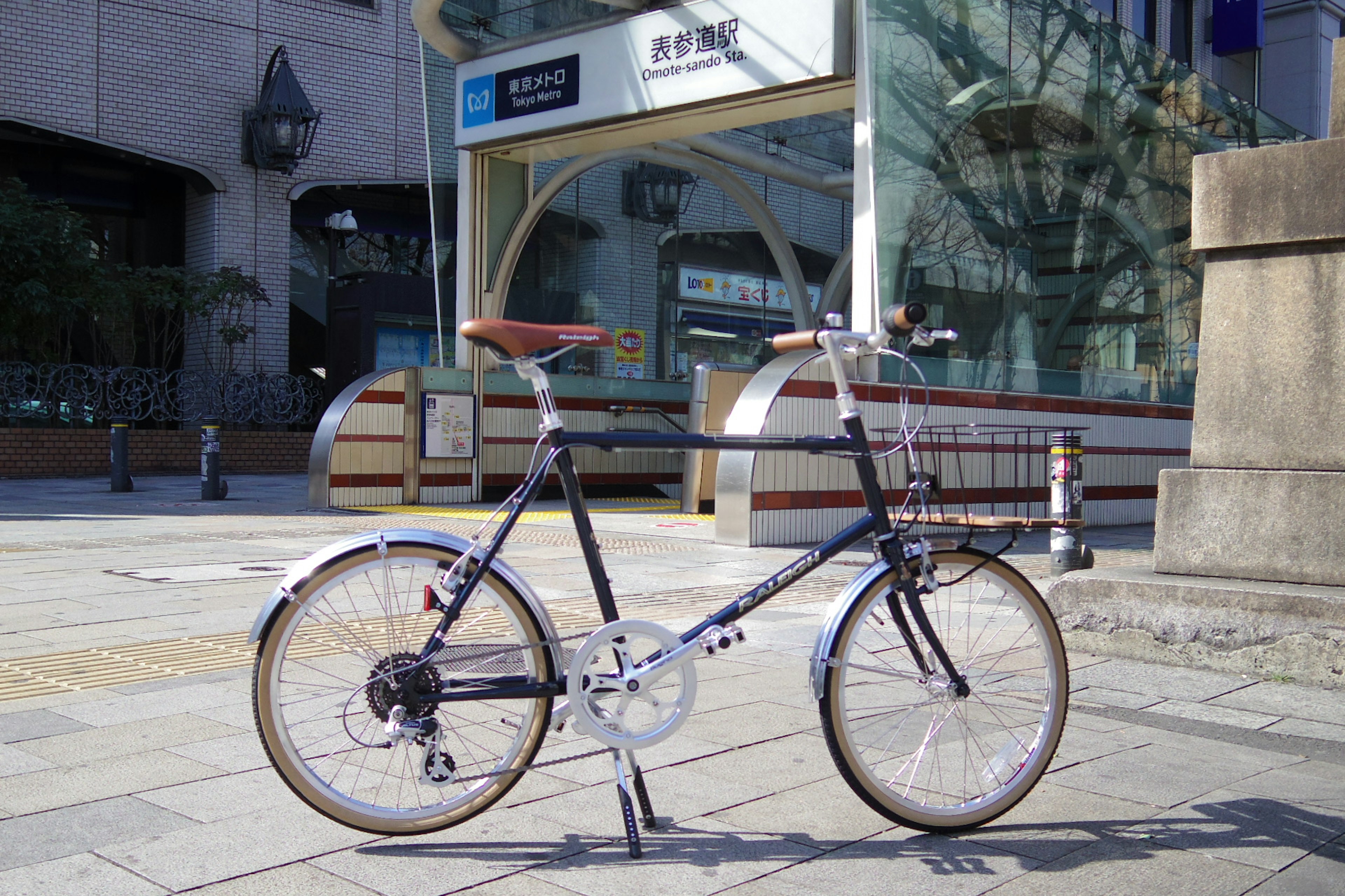 Bicicleta plegable elegante bajo un cielo azul cerca de un letrero de estación