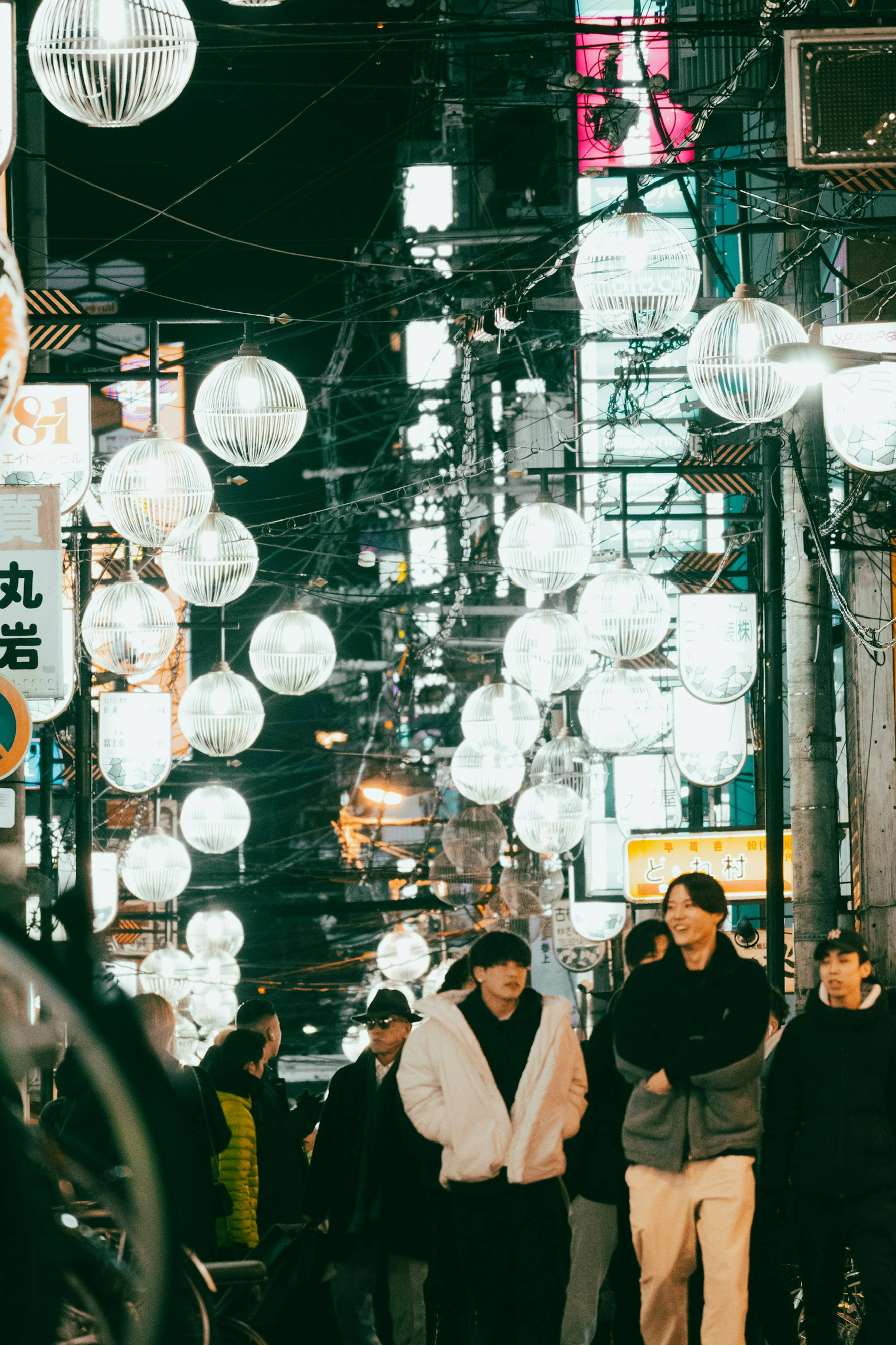 People walking under lanterns in a nighttime street scene