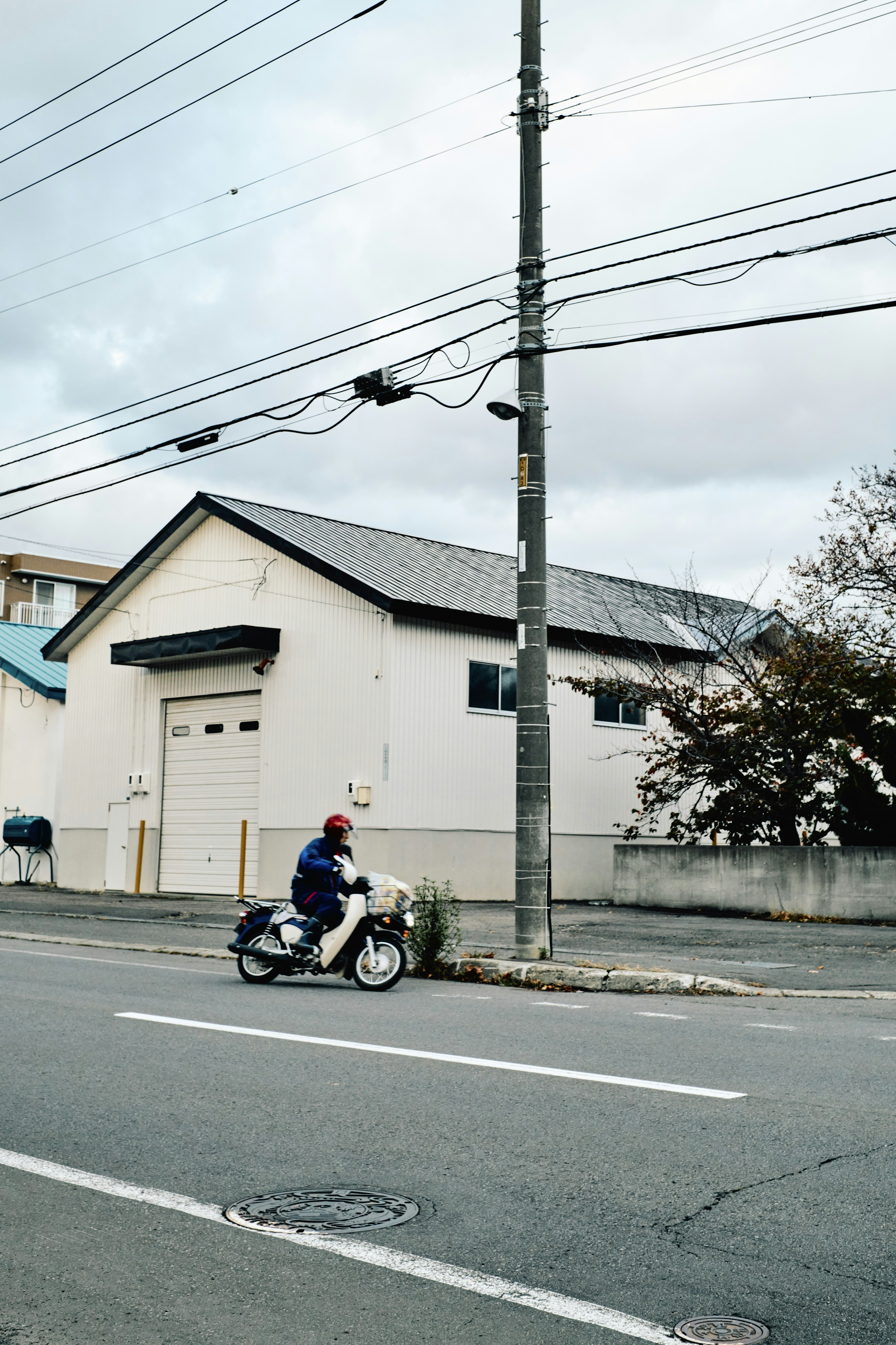 白い家の前を走るバイクに乗った男性の画像