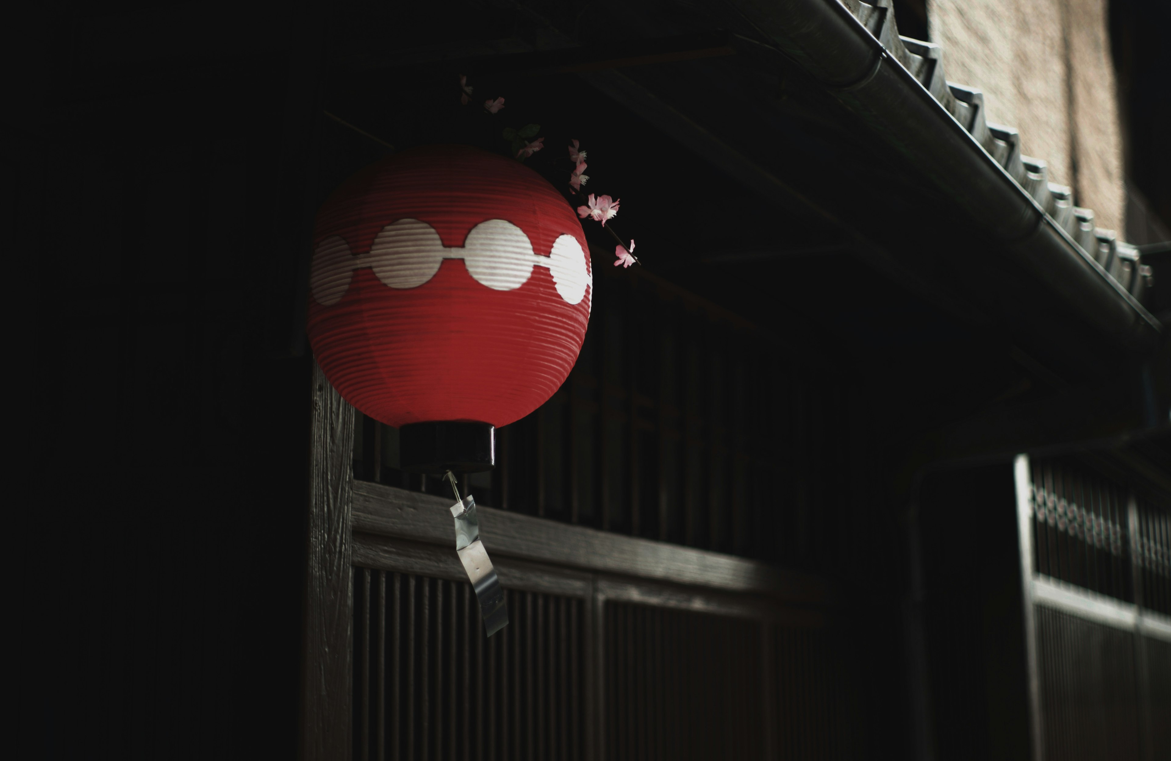 Rote Laterne, die vor einem dunklen Hintergrund in einem traditionellen japanischen Umfeld hängt