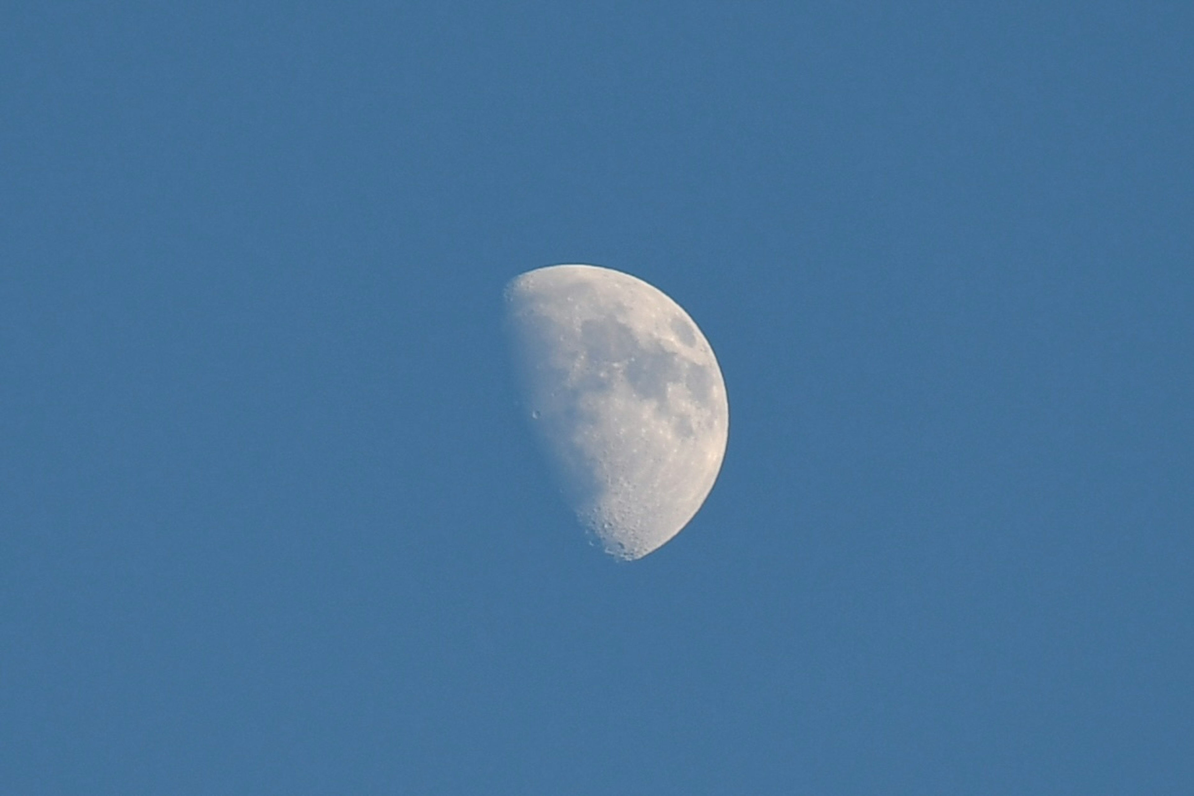 Close-up of a half moon in a blue sky