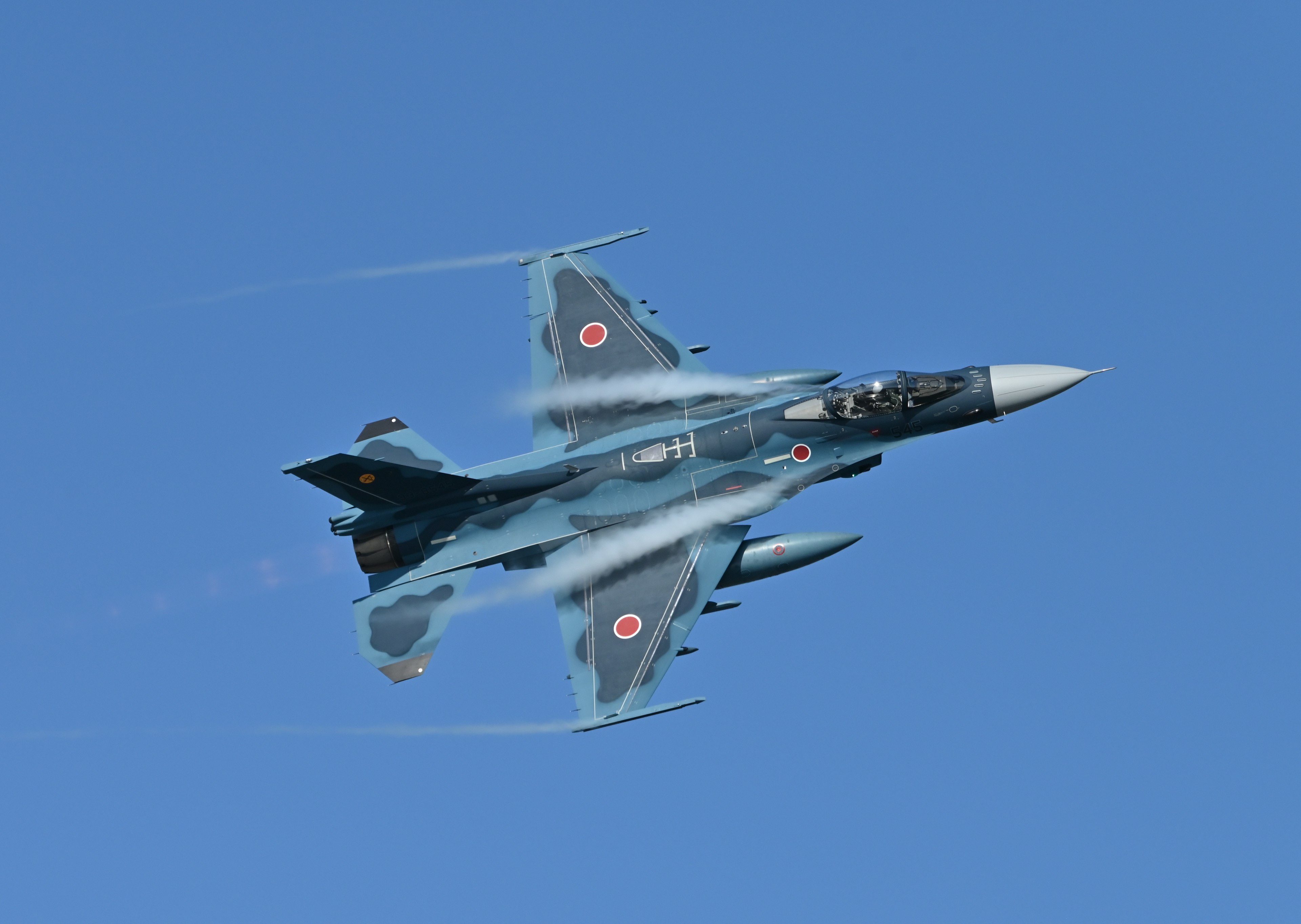 Avion de chasse effectuant une montée rapide sur fond de ciel bleu clair