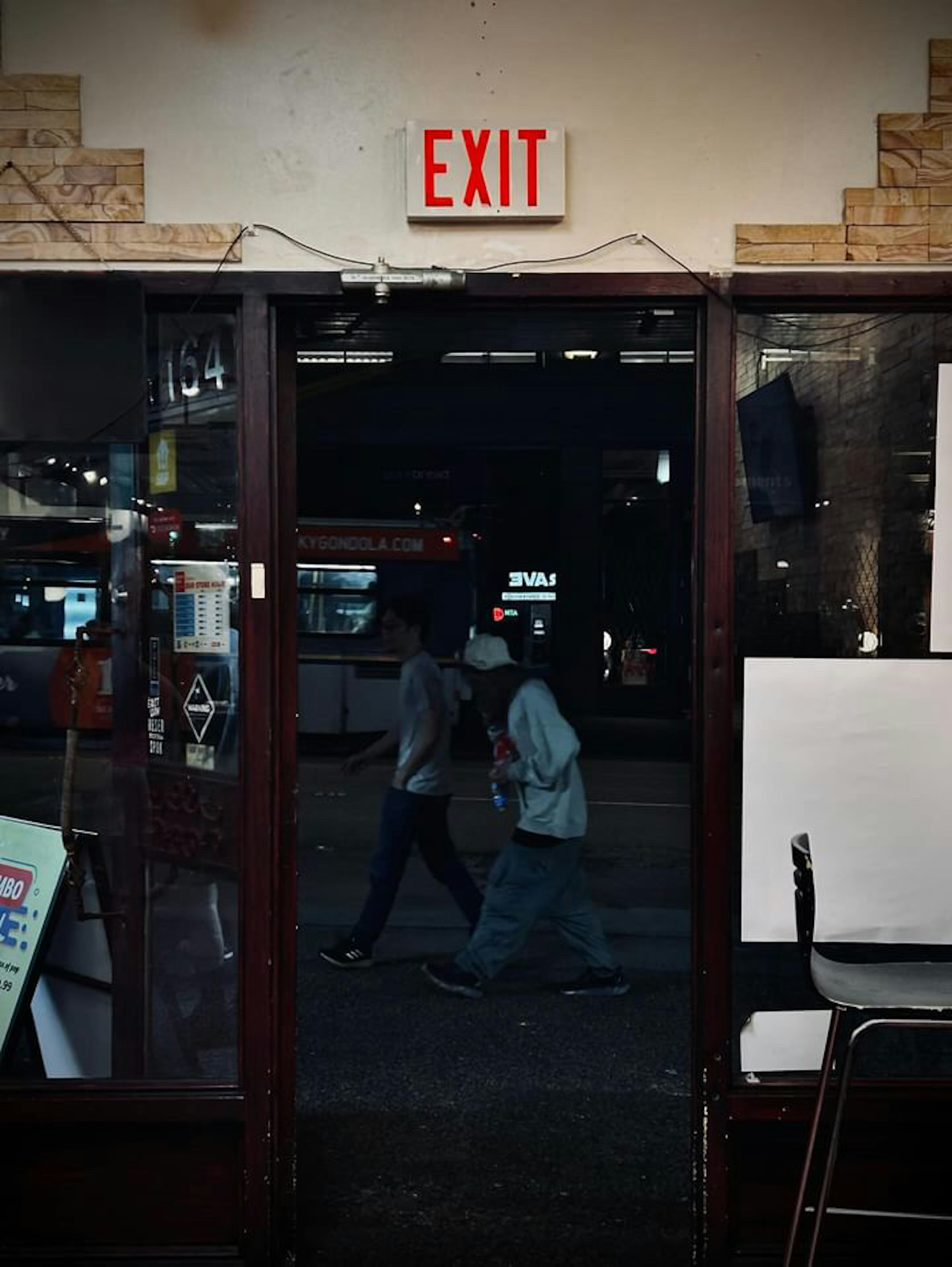 Two pedestrians walking past an exit sign door