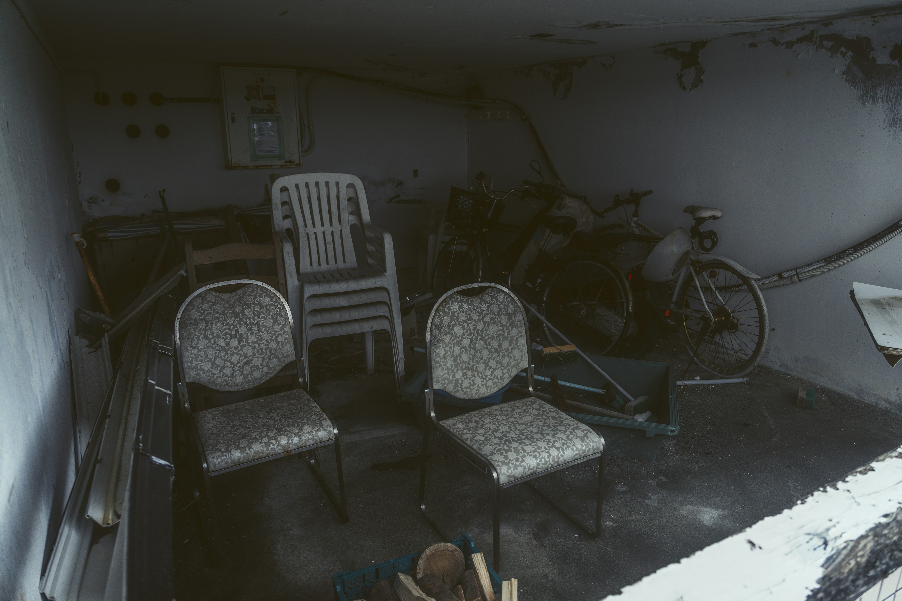 A dimly lit room with two chairs and a bicycle in the background