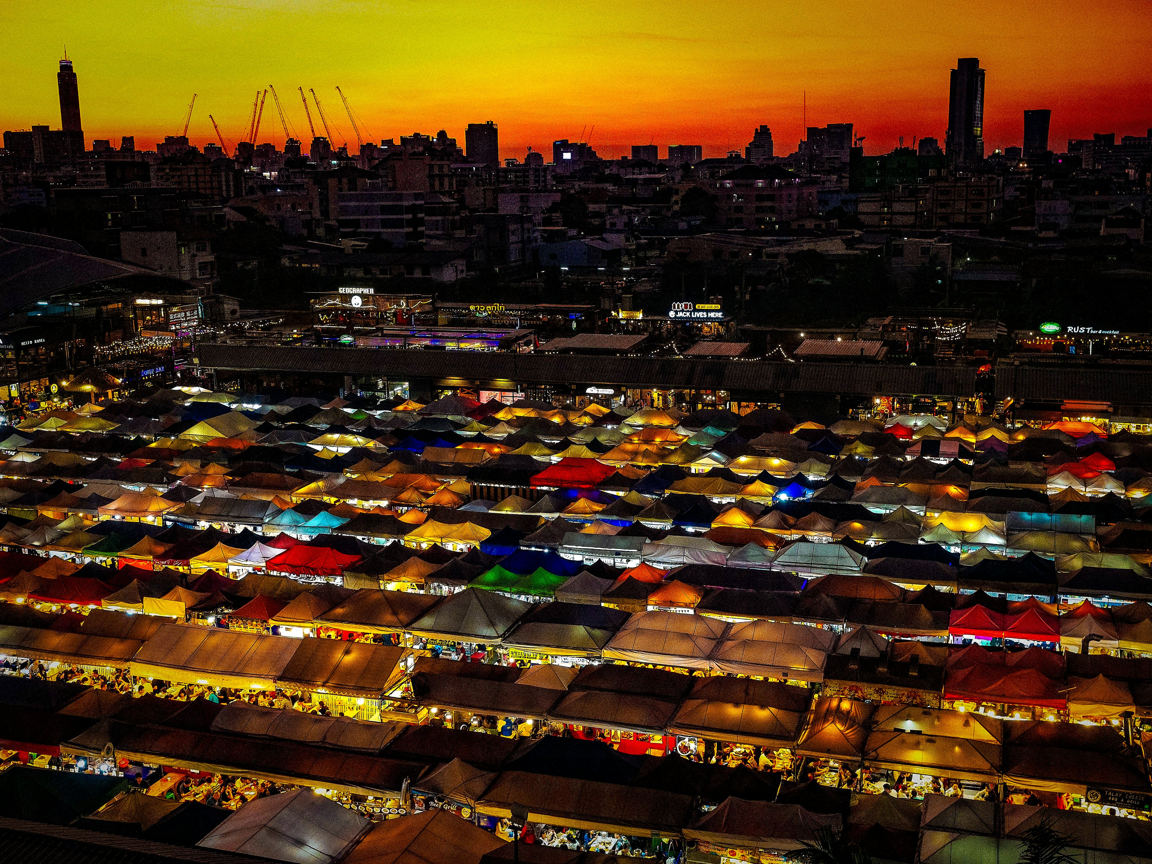 Scena di mercato notturno con tende colorate sotto un tramonto