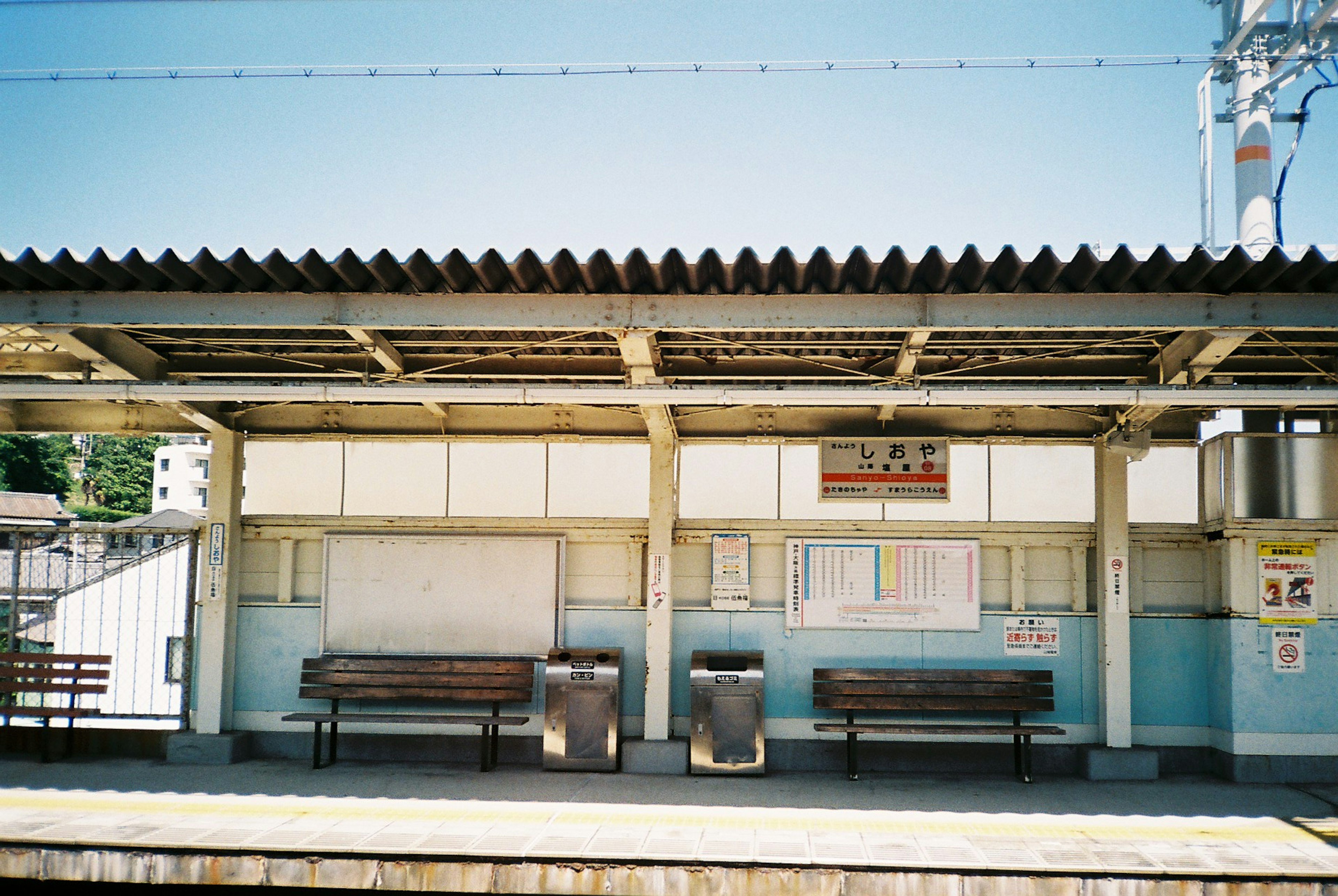 Photo d'une zone d'attente de gare tranquille avec des bancs et un panneau d'information