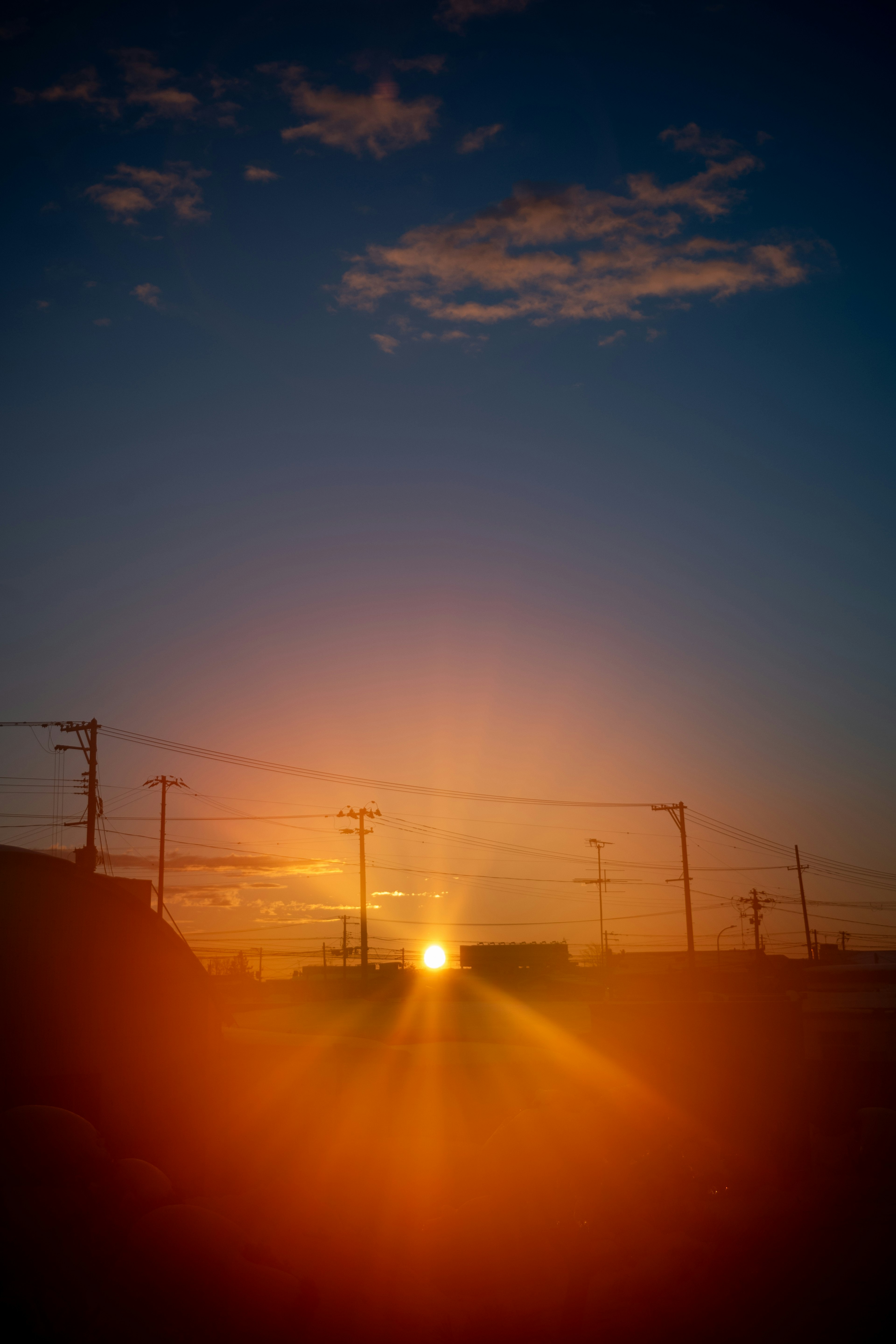 夕日が昇る風景と電柱のシルエットが見える