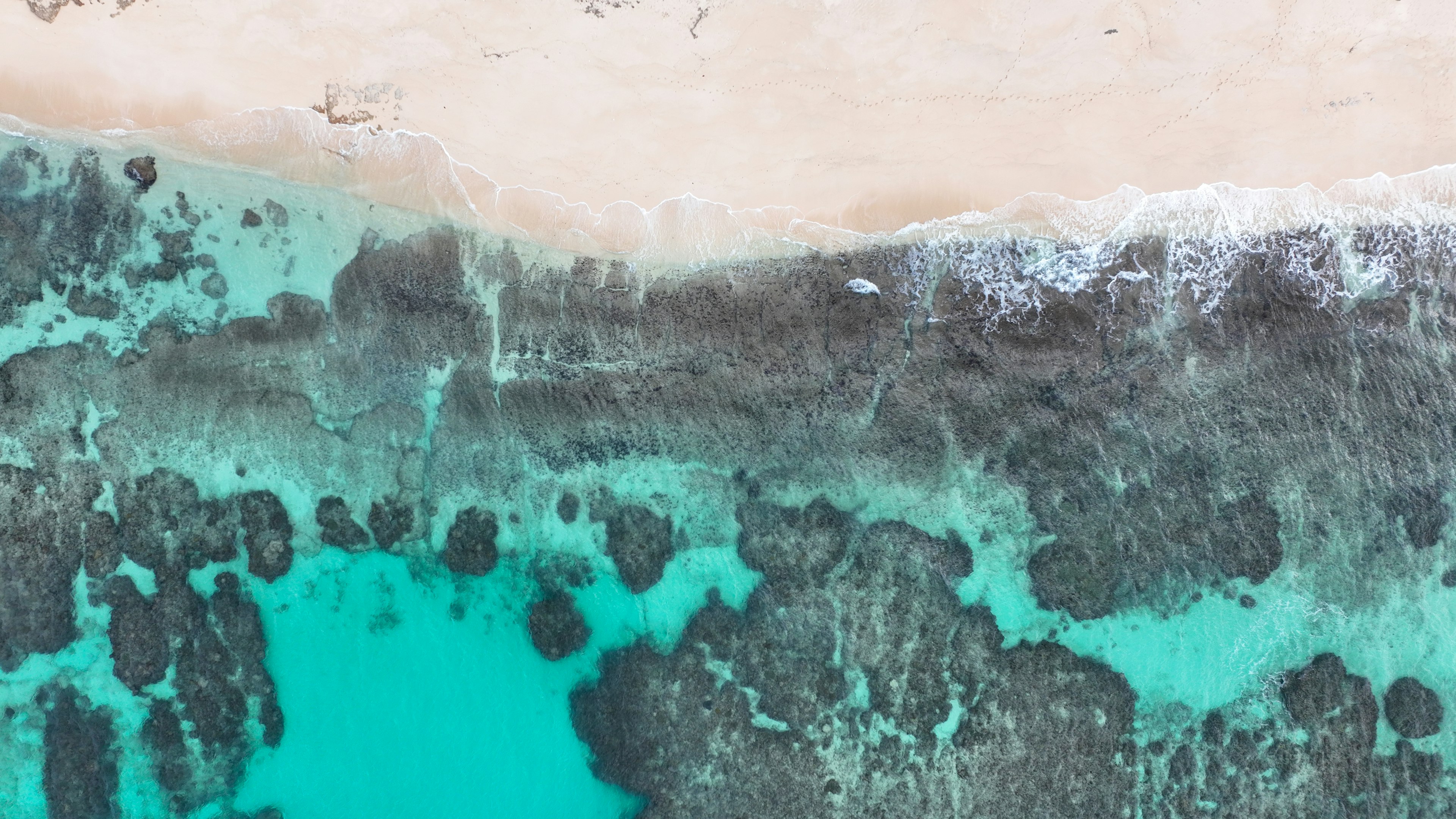 ภาพถ่ายทางอากาศของชายหาดที่สวยงามพร้อมน้ำทะเลสีเทอร์ควอยซ์และทรายขาว