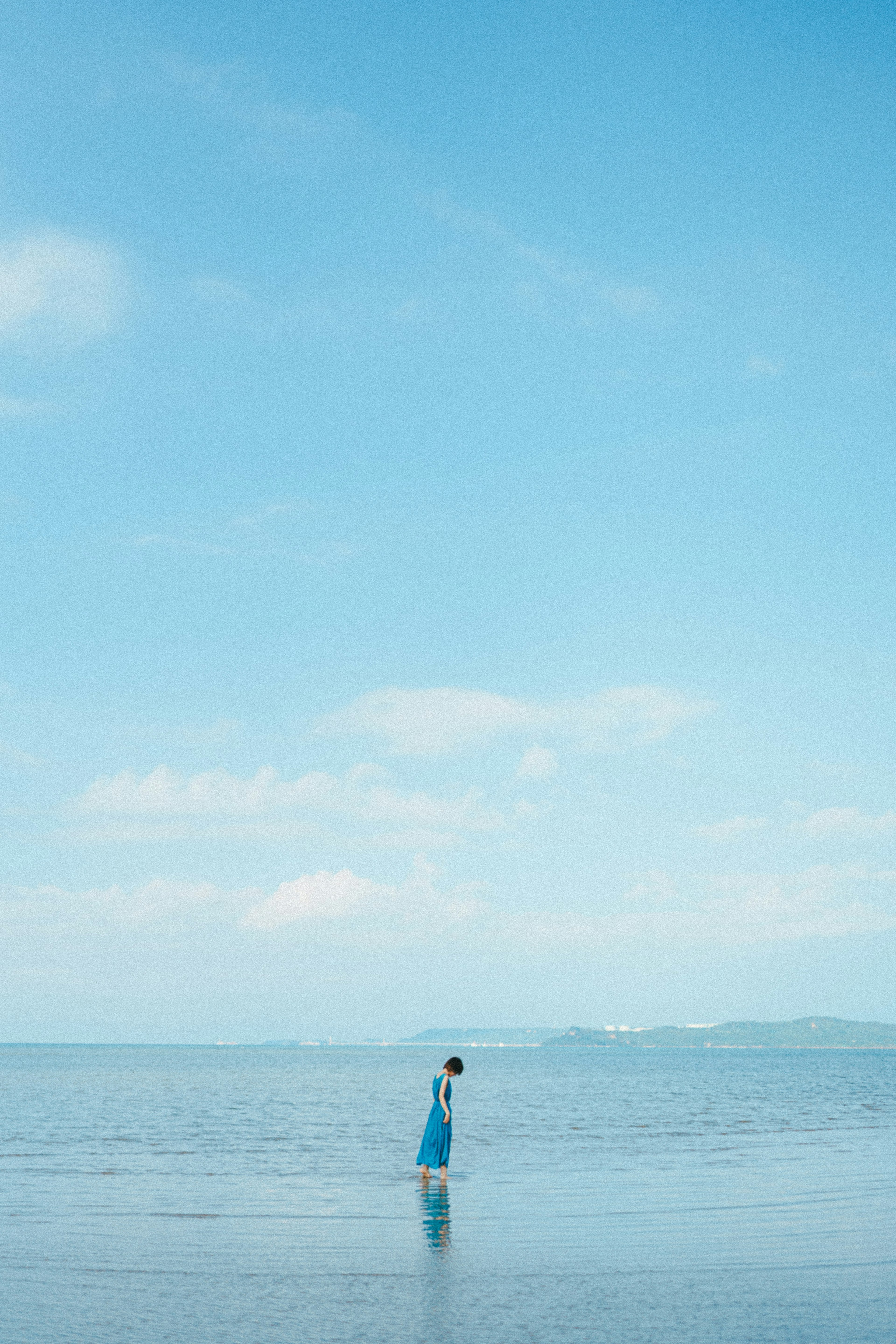 青空の下で海に立つ人物のシルエット