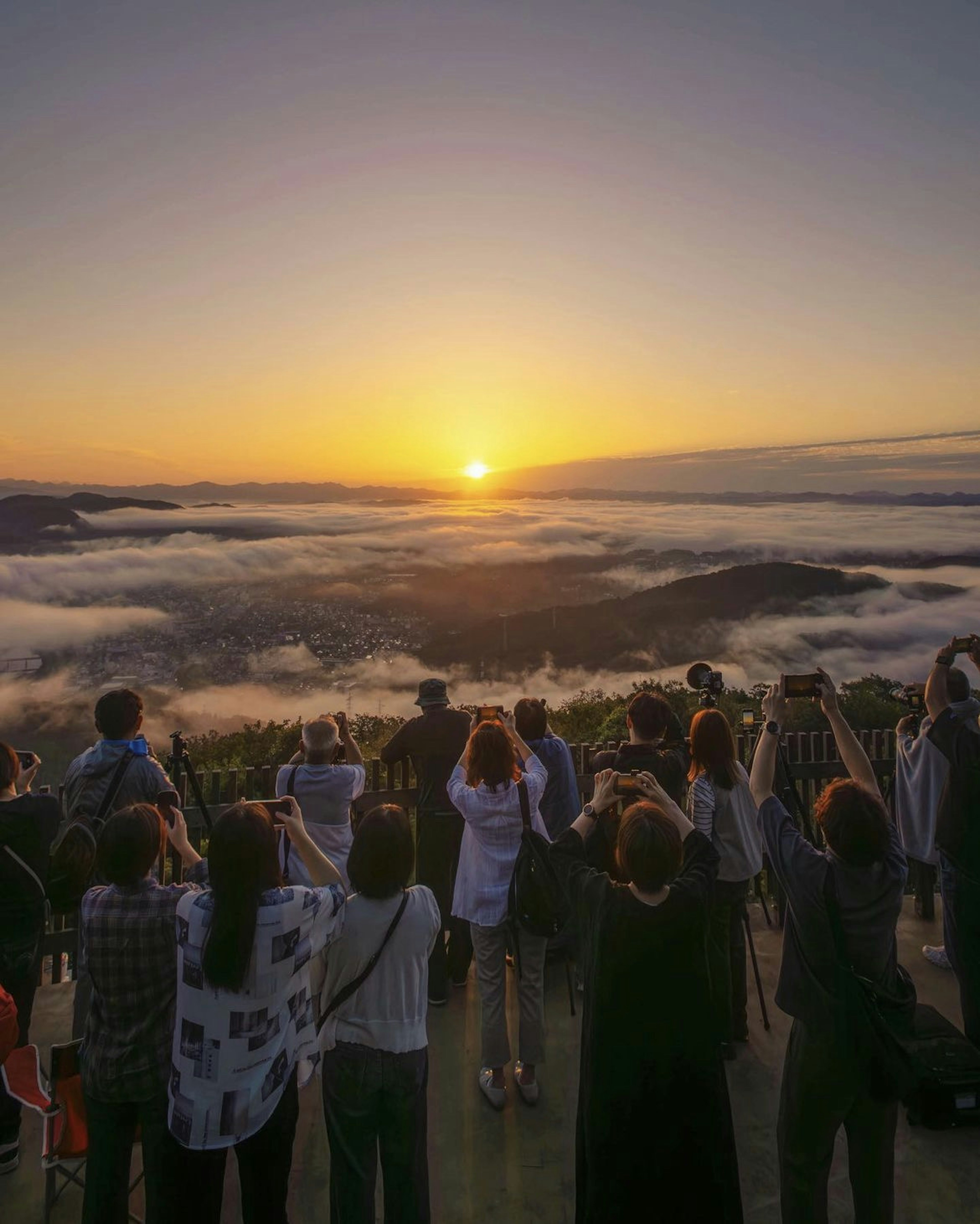 Crowd of people watching sunrise from a mountain peak