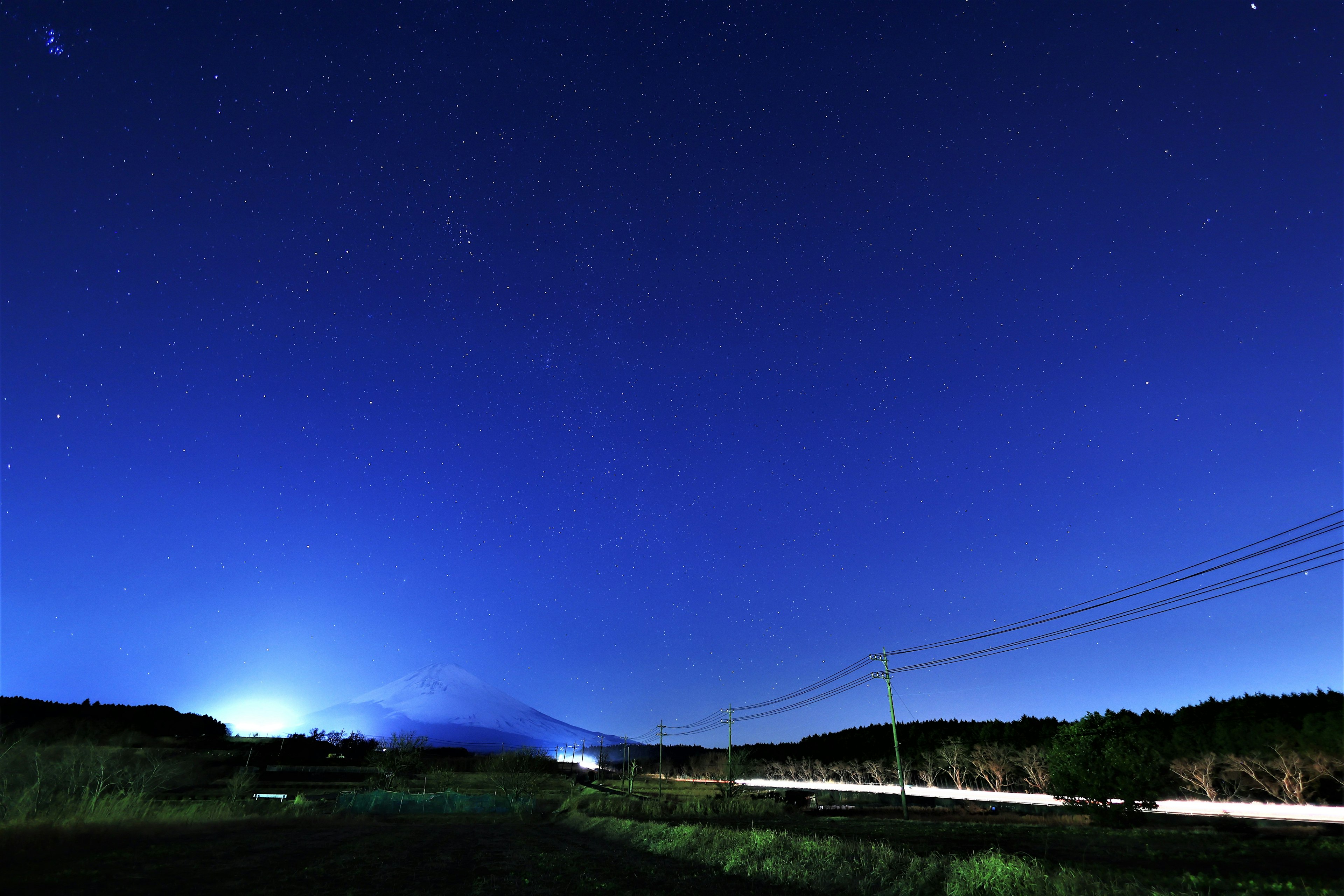 Paisaje nocturno bajo un cielo estrellado con la silueta de una montaña lejana