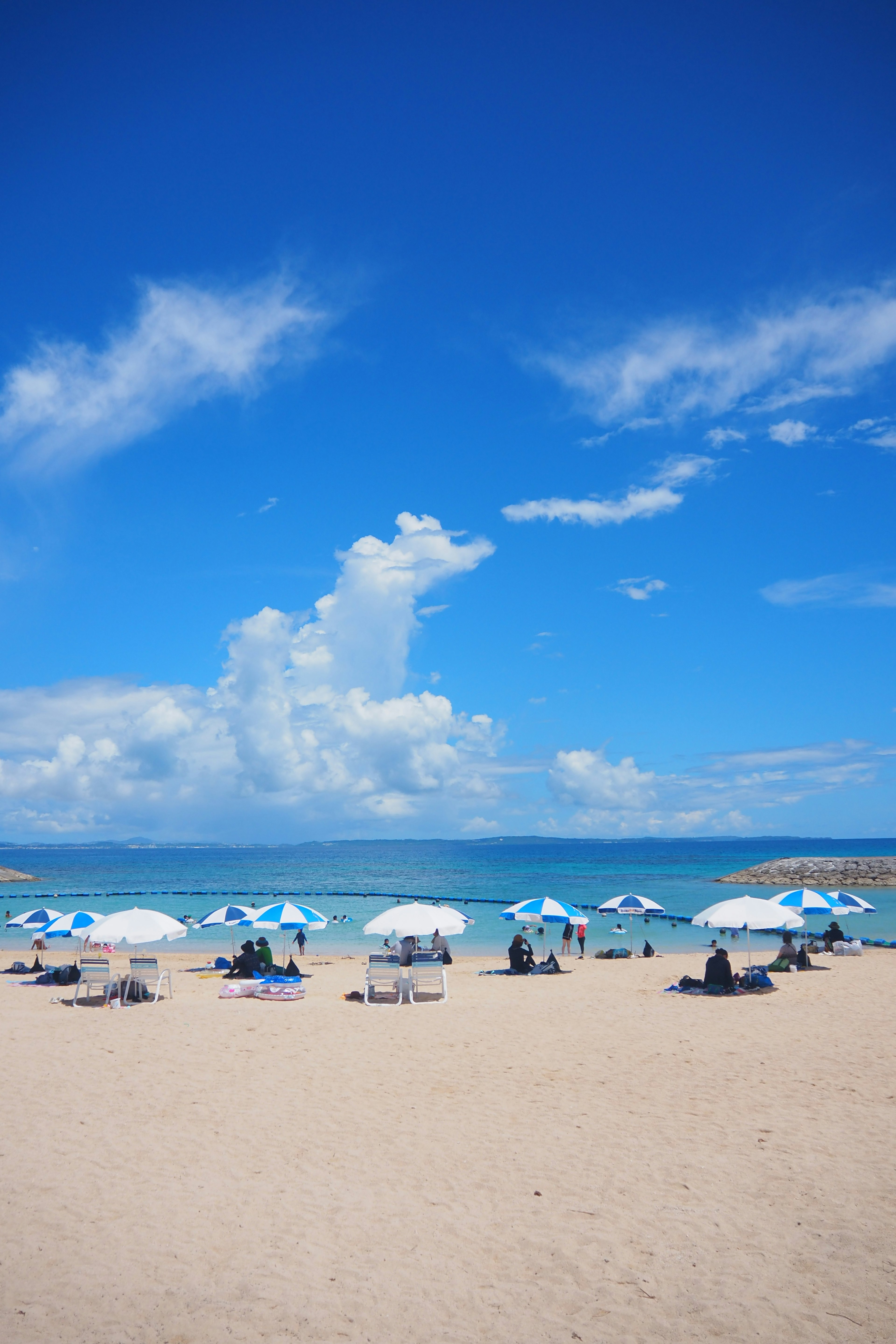 Beach scene with blue sky and white clouds featuring beach umbrellas