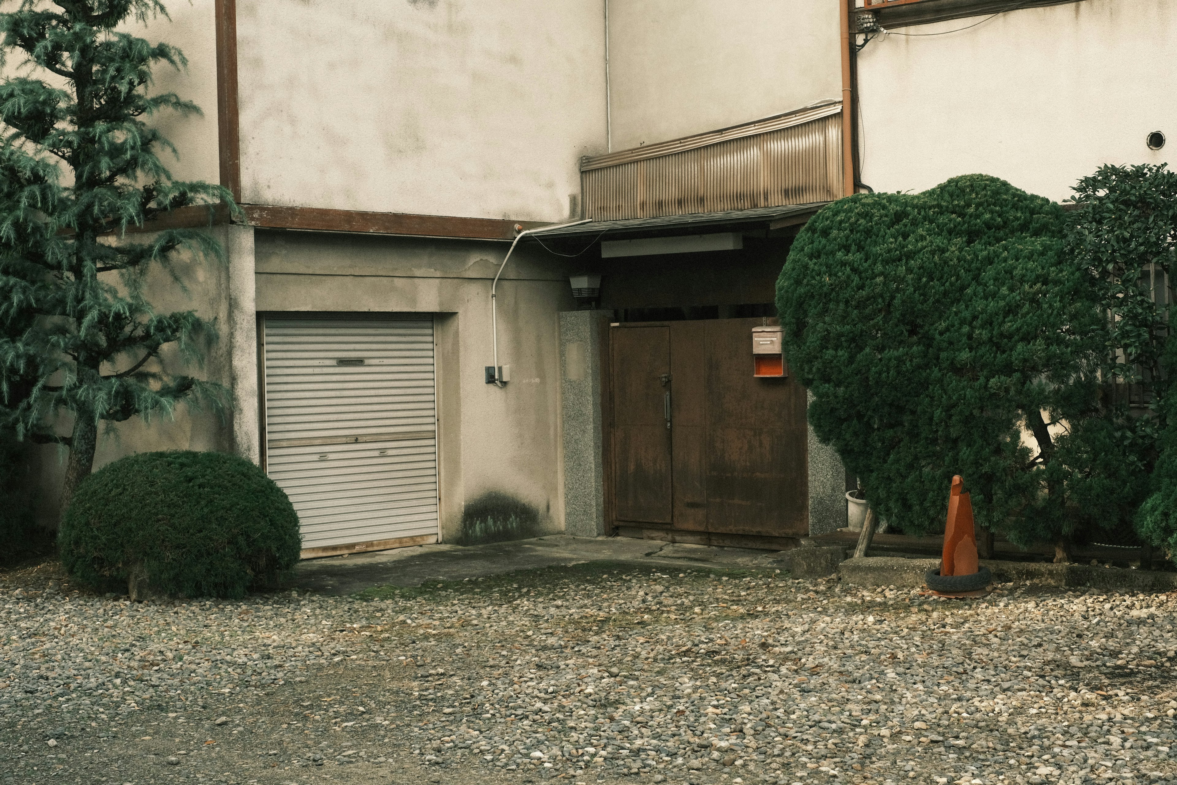 Vista exterior de un edificio antiguo con vegetación y grava