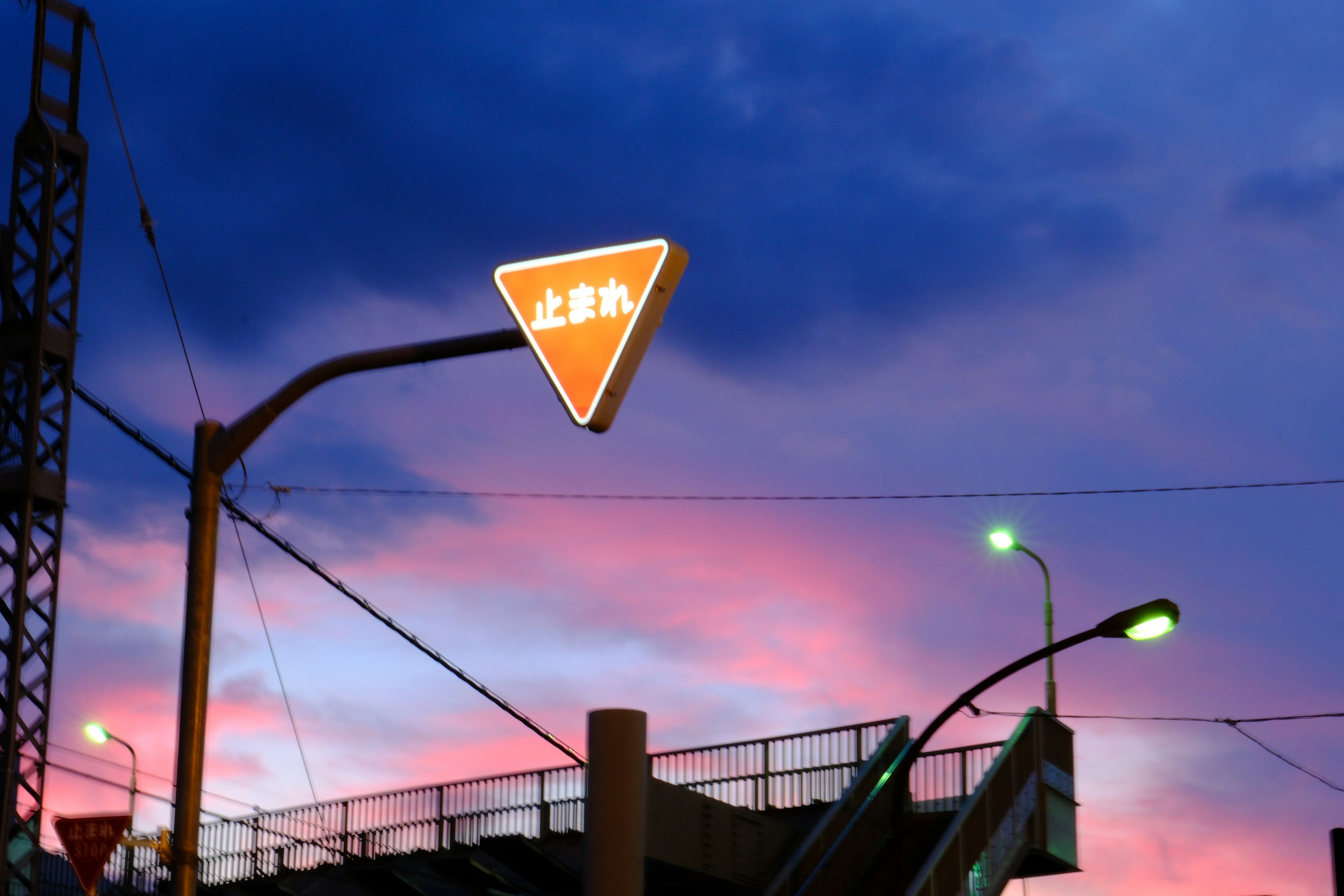 夕焼けの空と交差点の警告標識を映した画像