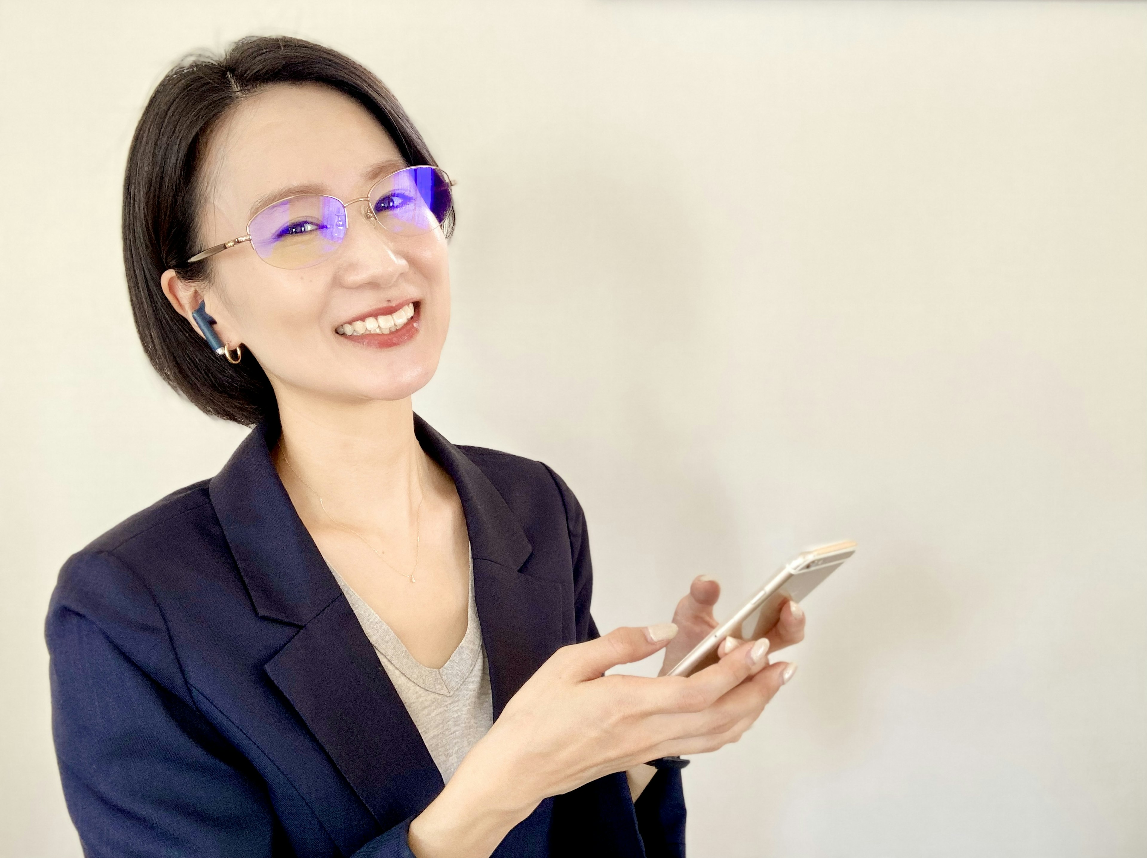 Ritratto di una donna sorridente che tiene uno smartphone indossando occhiali blu in uno stile professionale