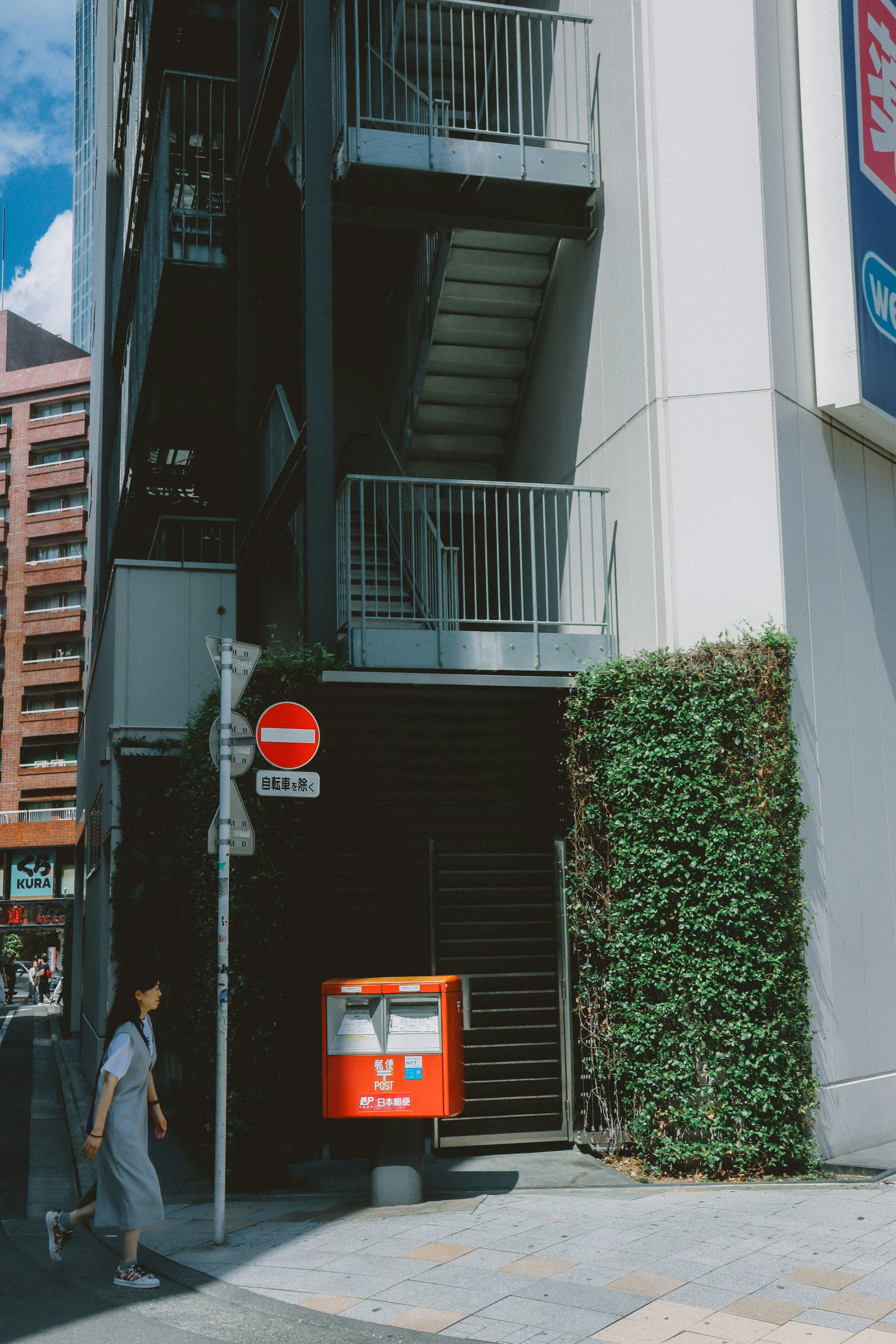 Scène de rue avec une boîte aux lettres rouge à l'entrée d'un bâtiment avec des escaliers