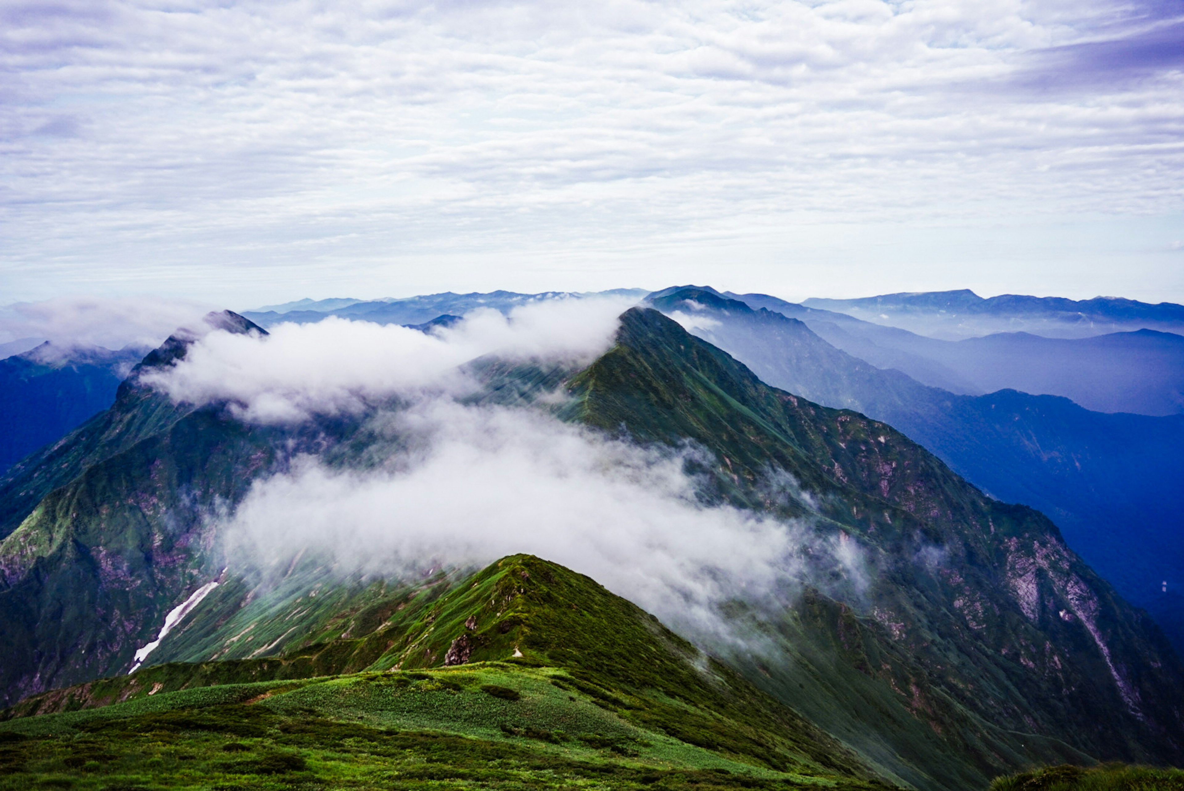 Gunung hijau yang indah dengan awan melayang