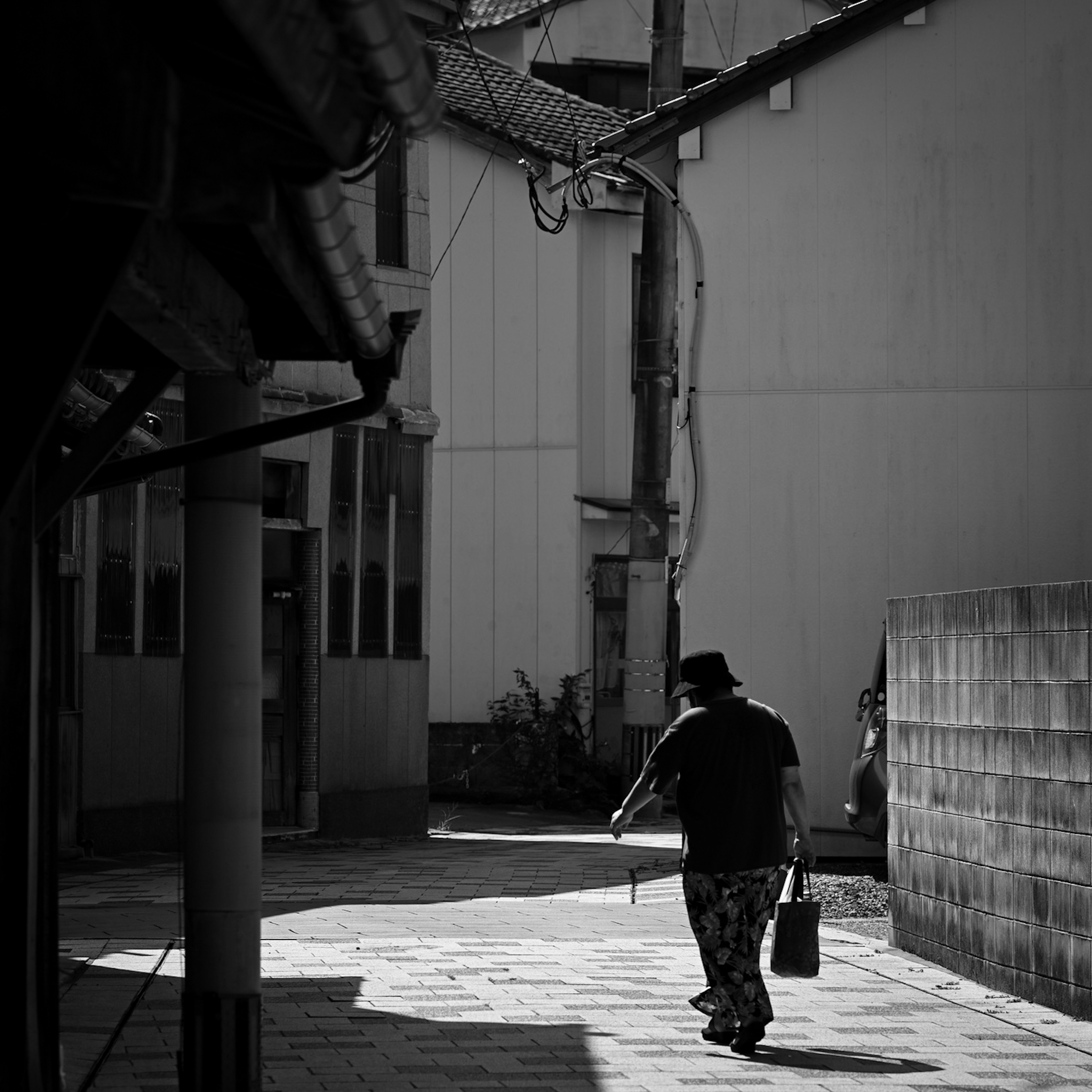 Une personne marchant dans une scène de rue en noir et blanc Une ruelle tranquille