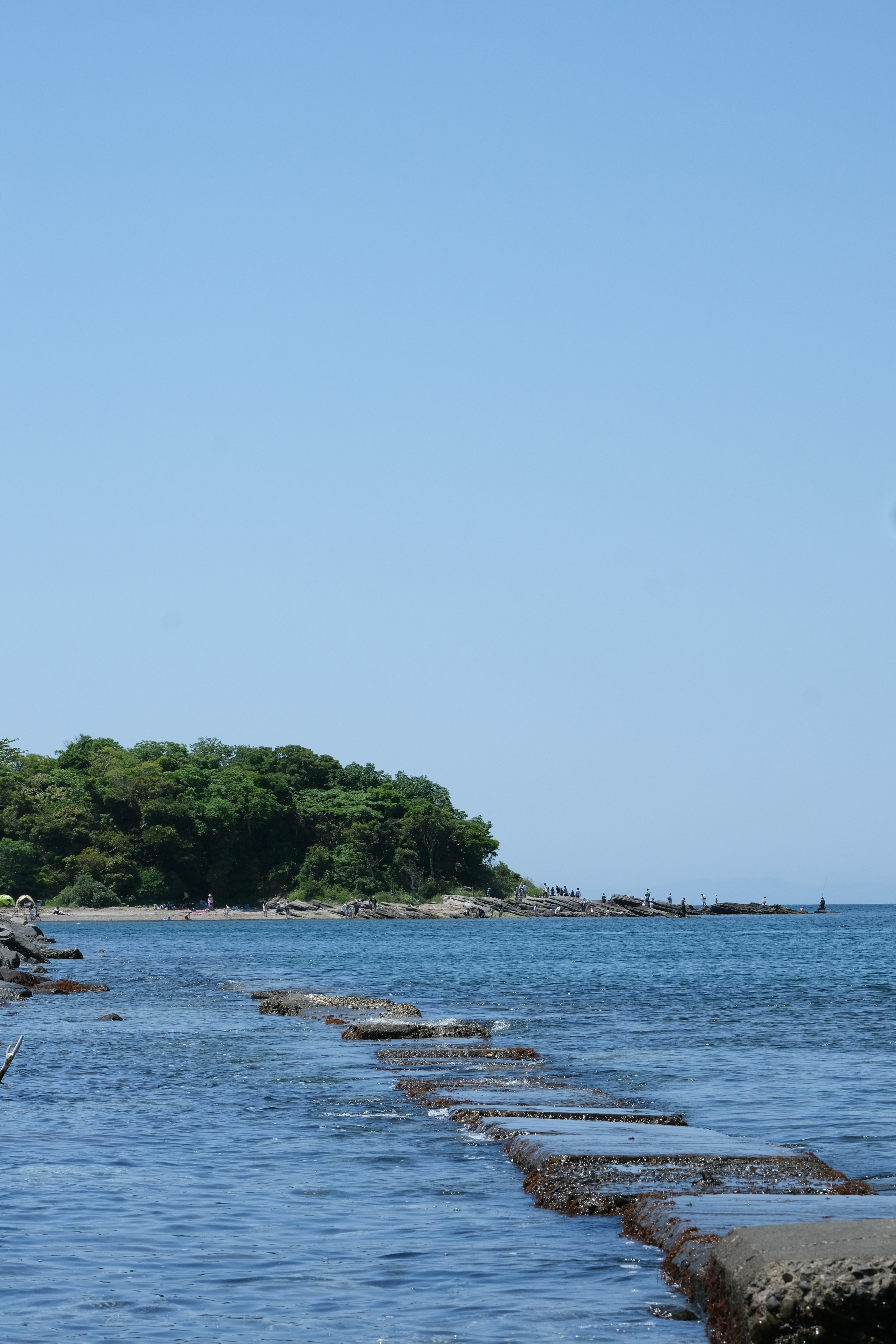 Küstenlandschaft mit blauem Meer und sichtbarer Insel steiniger Weg im flachen Wasser