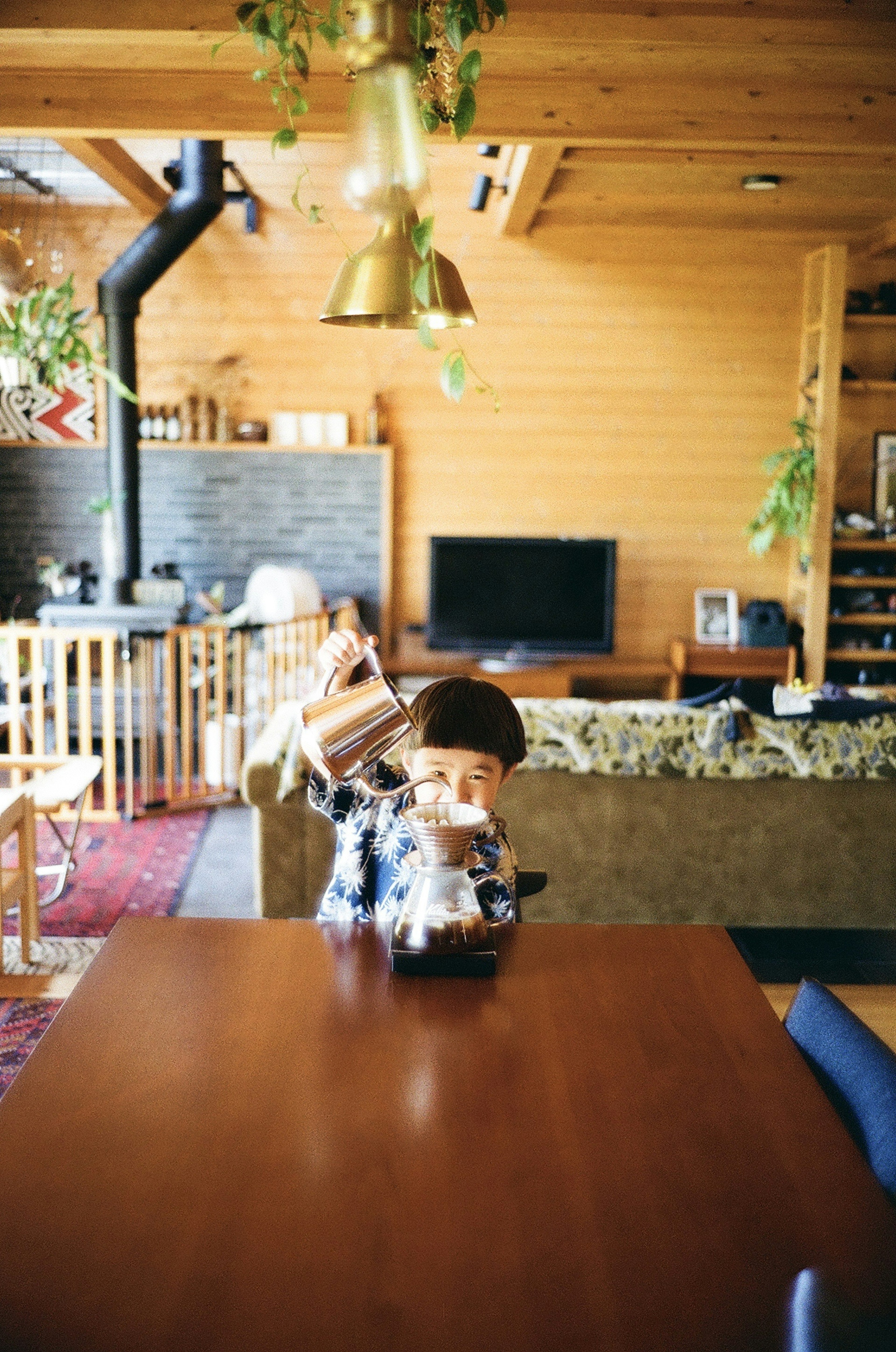 Sala de estar acogedora con mesa de madera y cafetera Plantas colgantes y paredes de madera