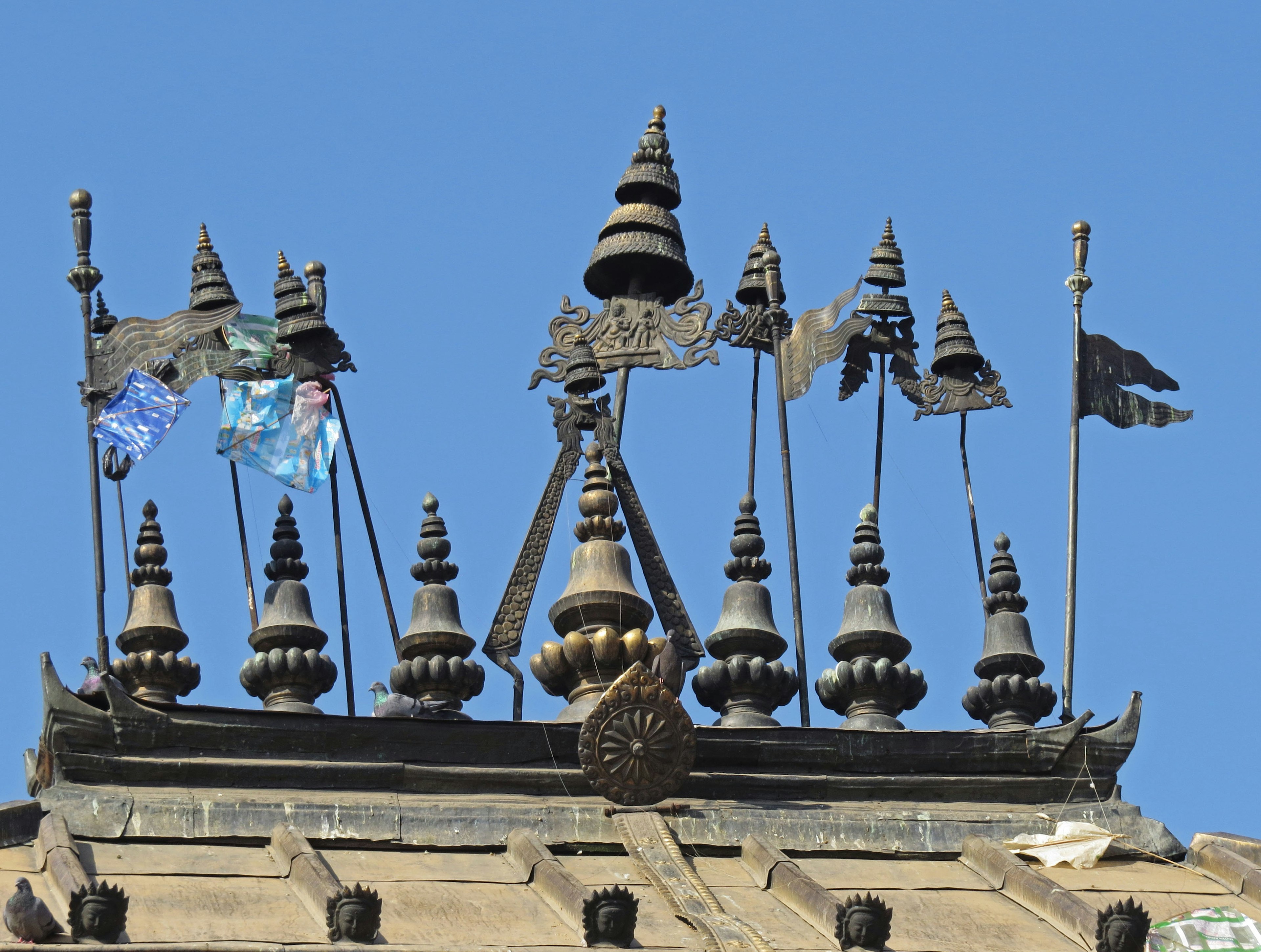 青空の下にある寺院の屋根に立つ多数の尖塔と旗