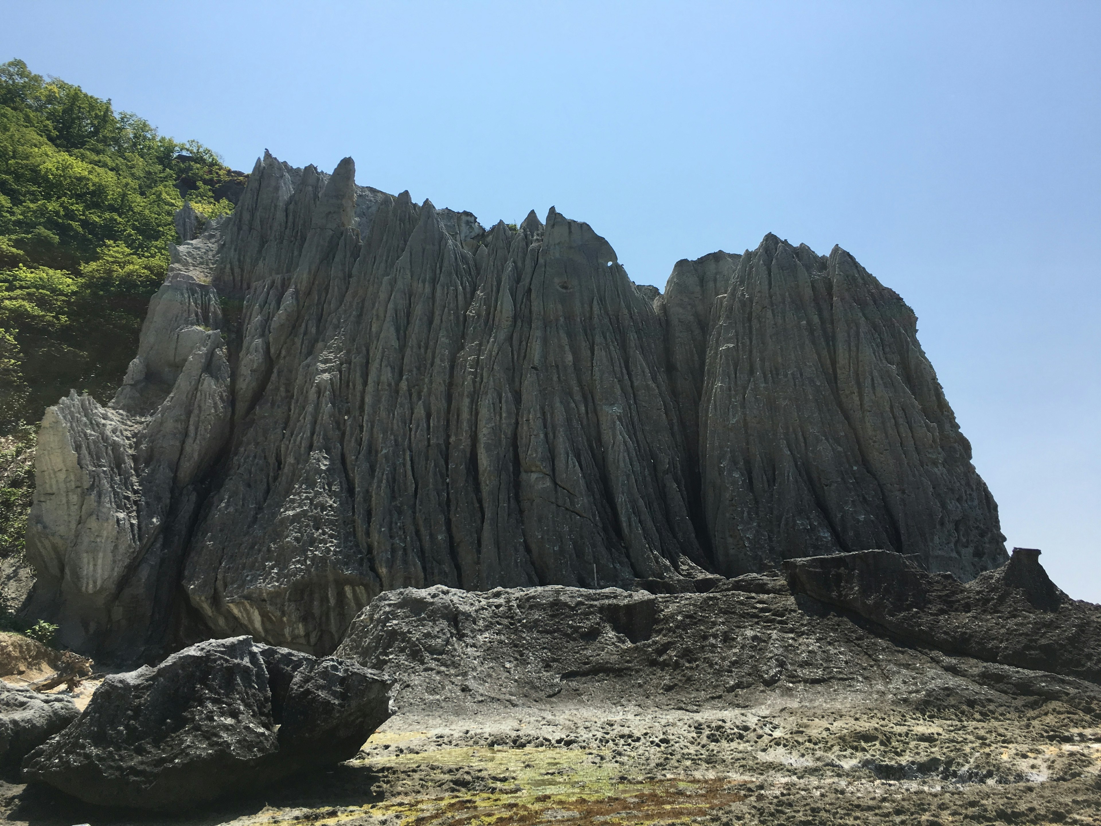 Paesaggio costiero con formazioni rocciose stratificate distintive sotto un cielo blu chiaro