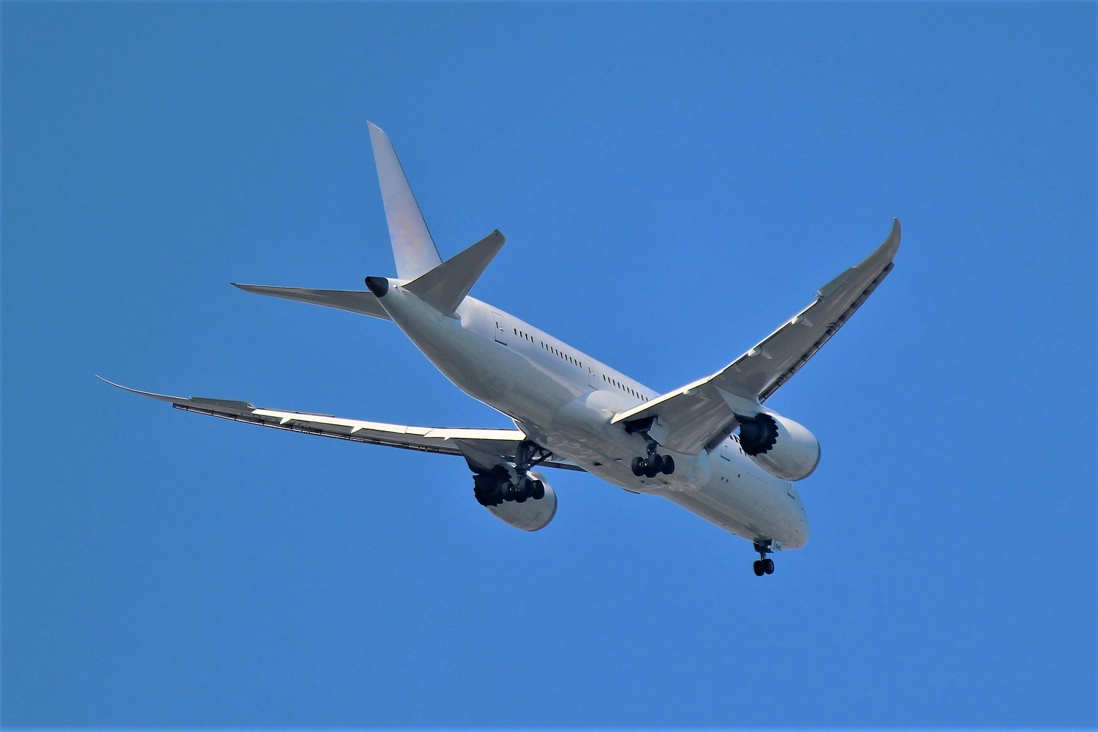 Airplane flying in the blue sky from below