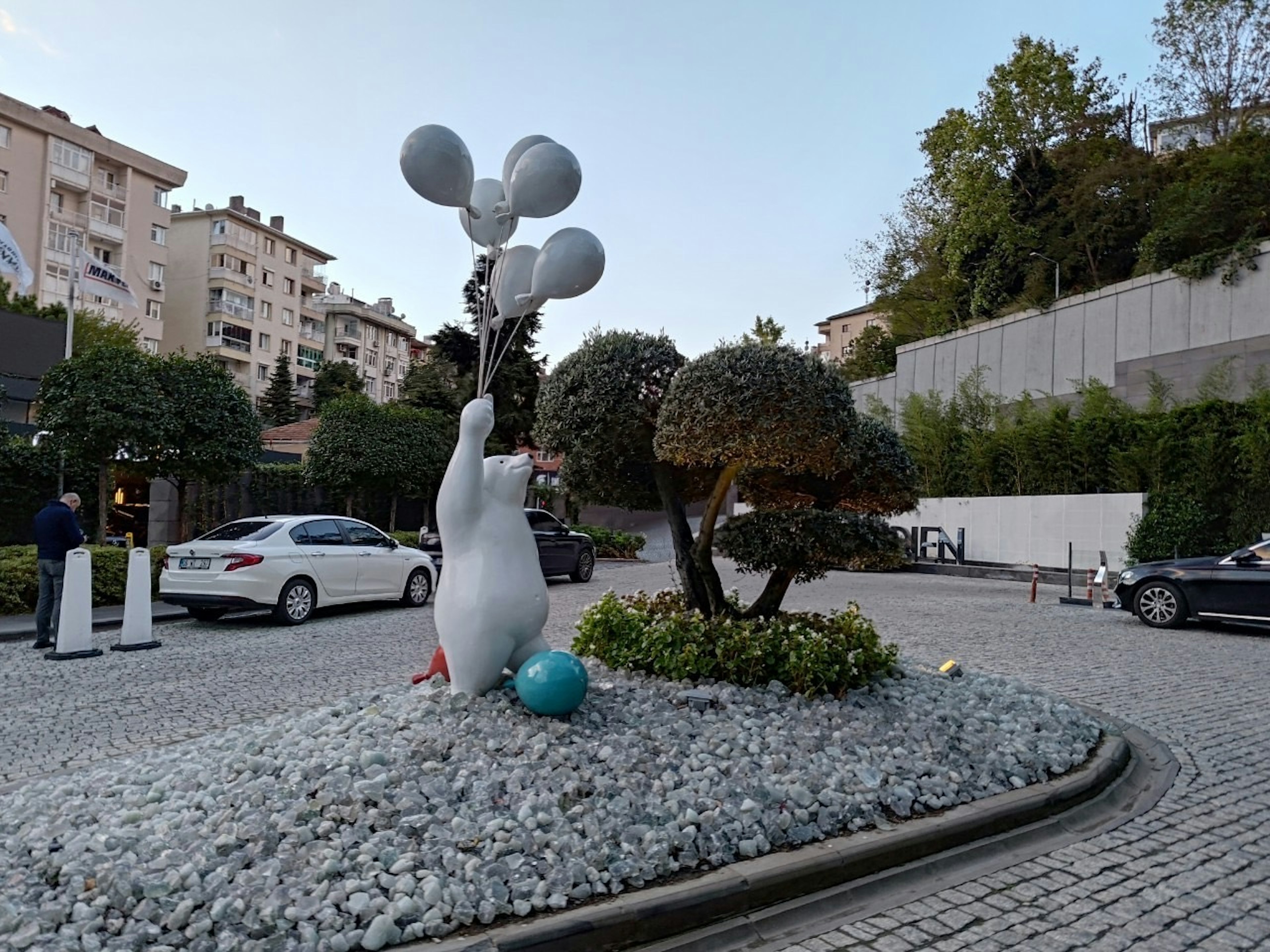 Un personaggio bianco con palloncini in un giardino