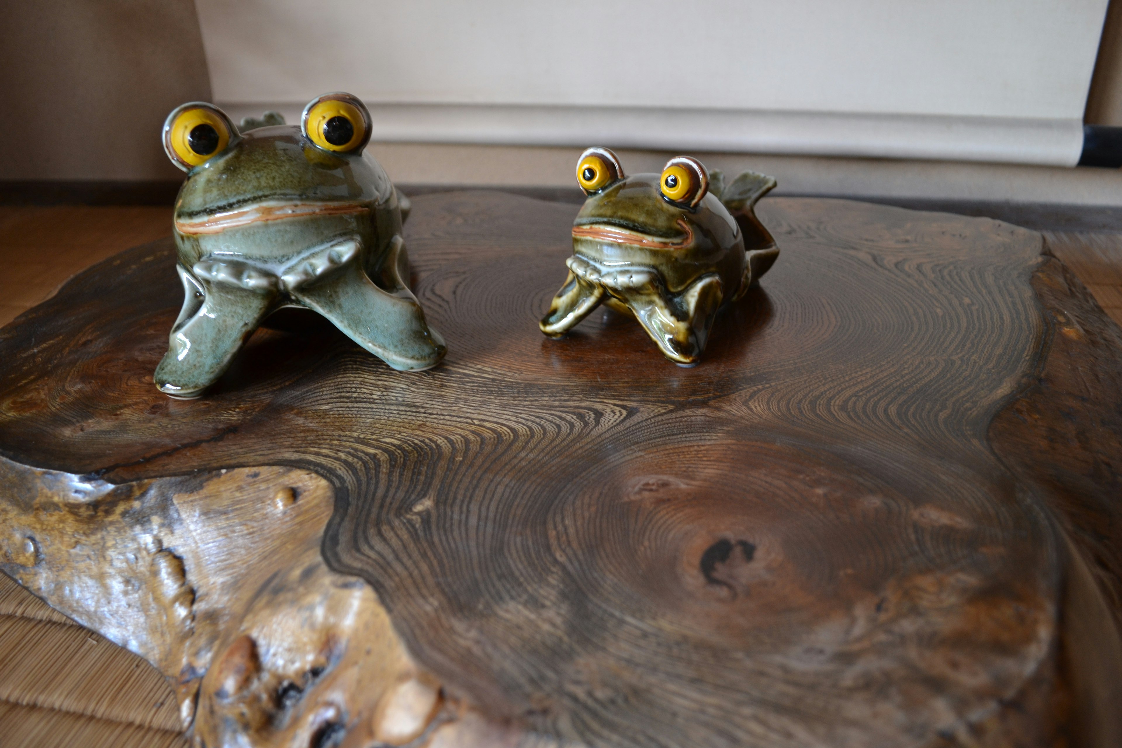 Dua patung katak keramik di atas meja kayu