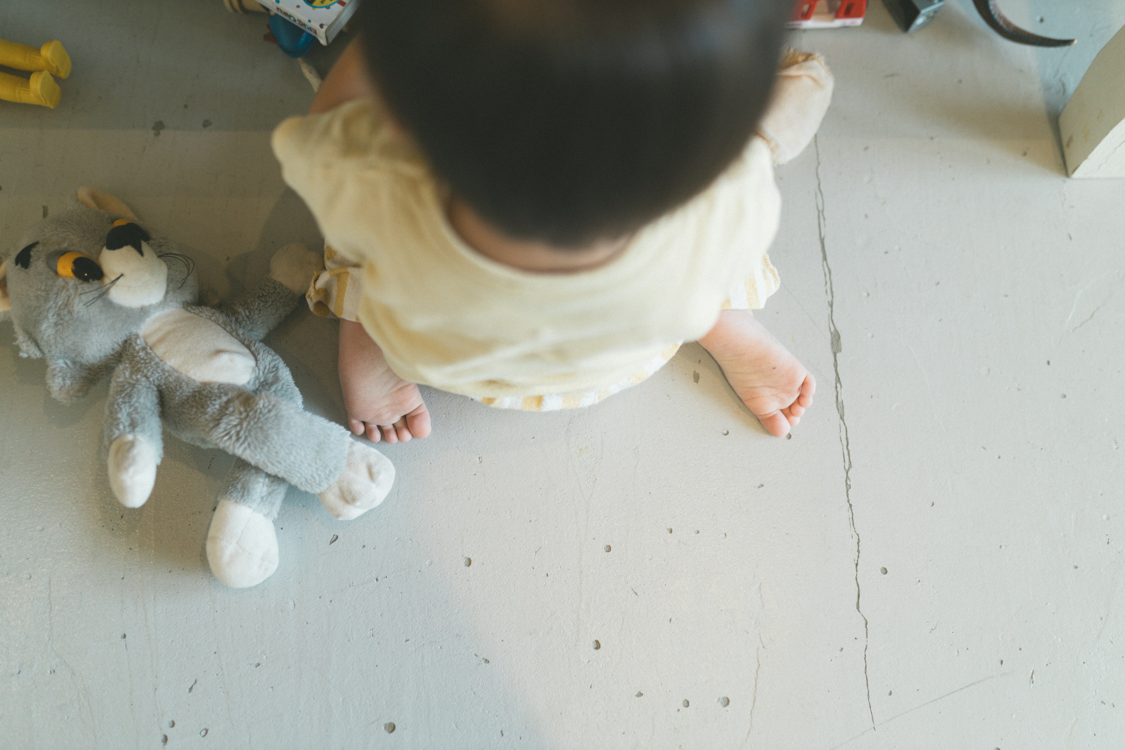 Un bambino seduto sul pavimento con un giocattolo di peluche accanto a lui