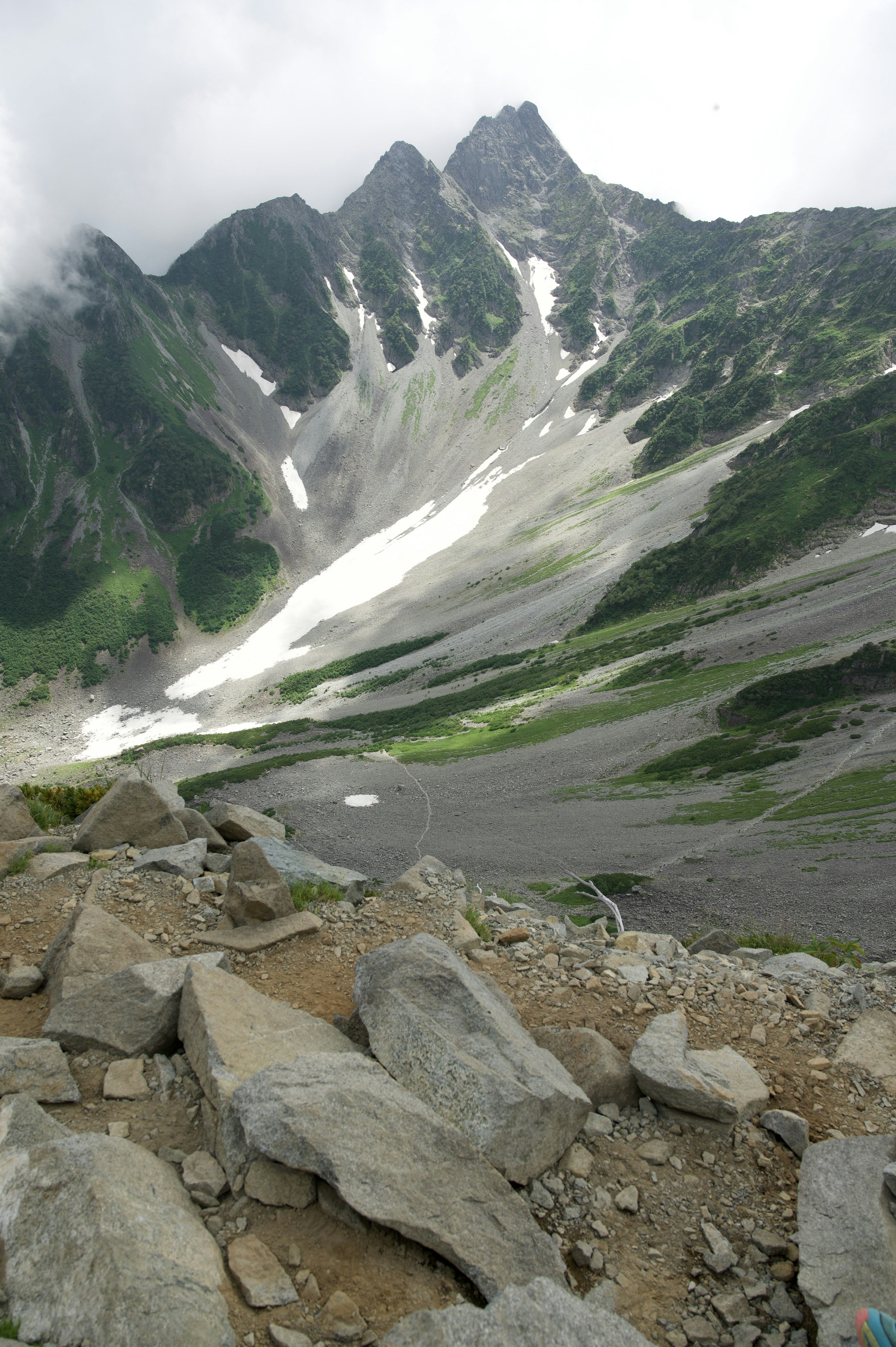 Panoramablick auf ein Bergtal mit schmelzendem Schnee und felsigem Gelände