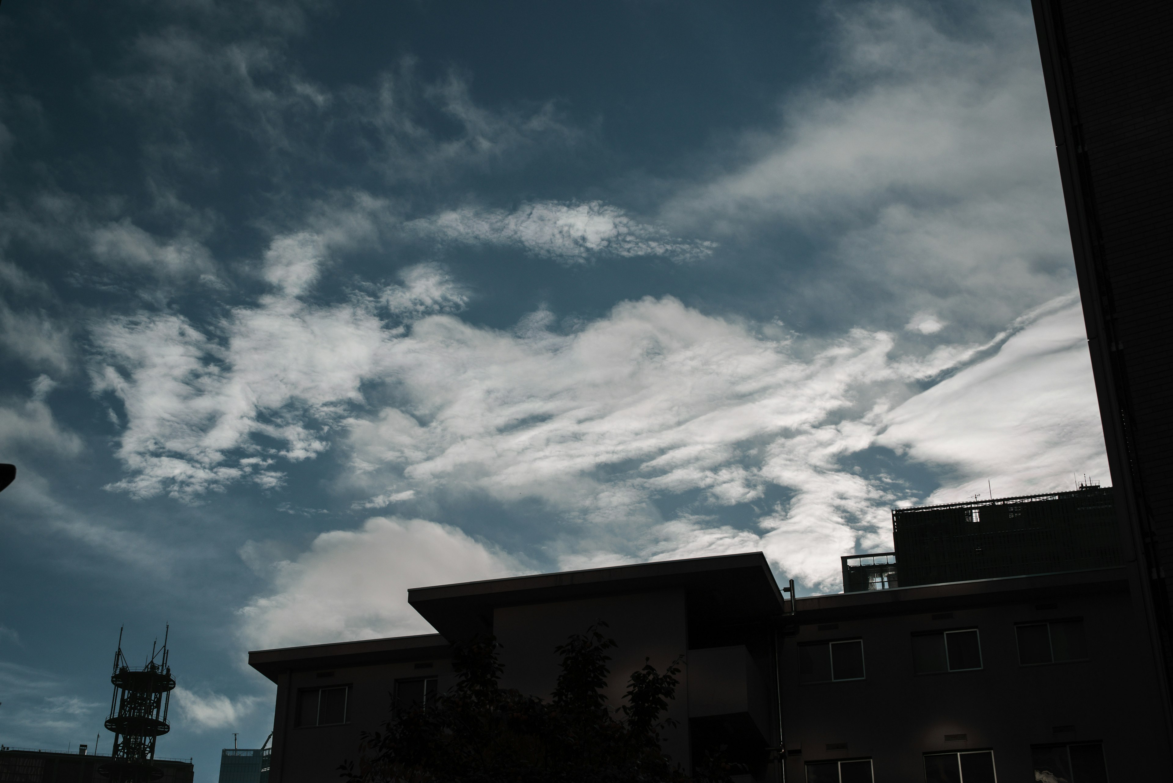 Silhouette of buildings against a blue sky with white clouds at dusk