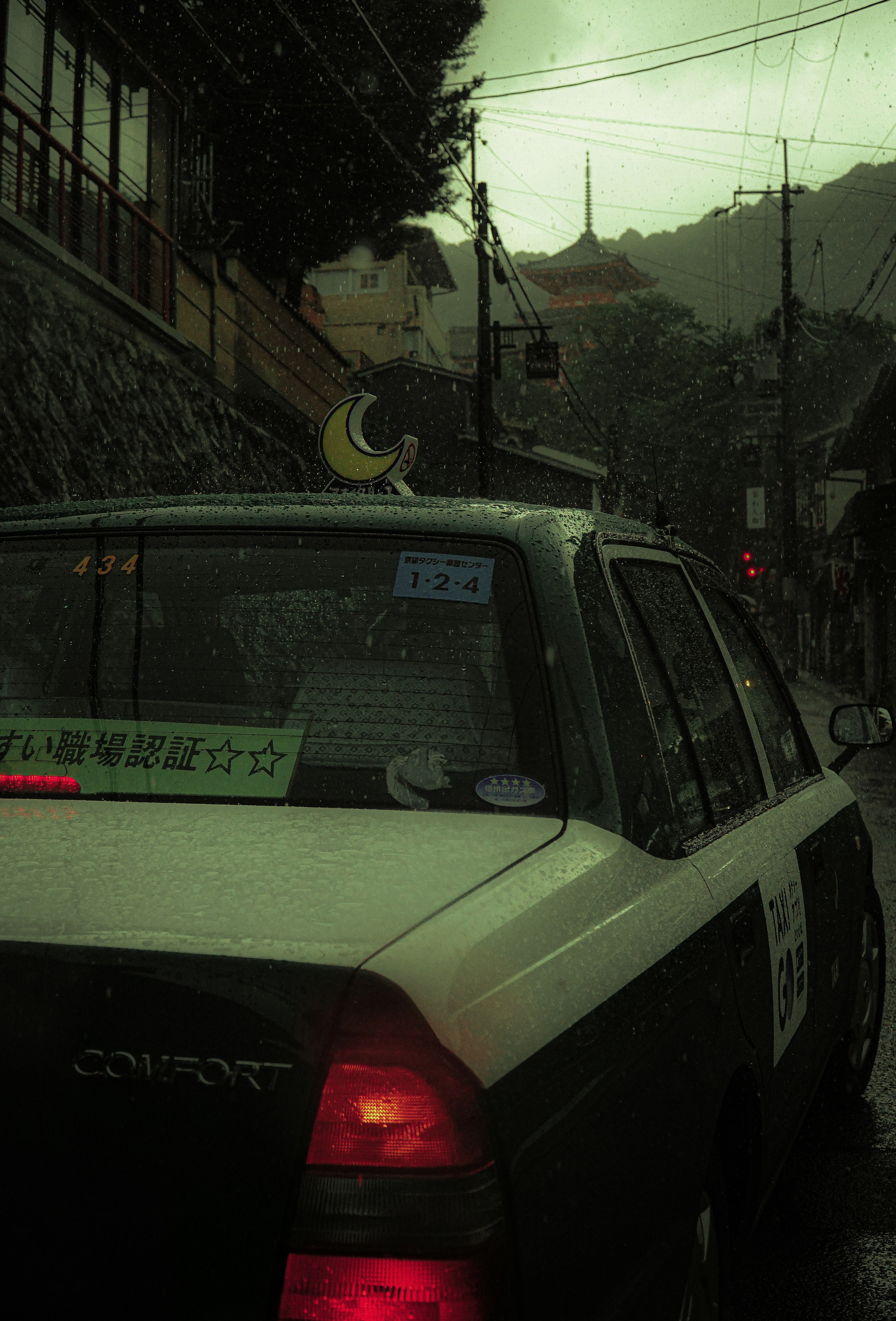 Taxi con decorazione a forma di luna sul retro in una scena di strada piovosa